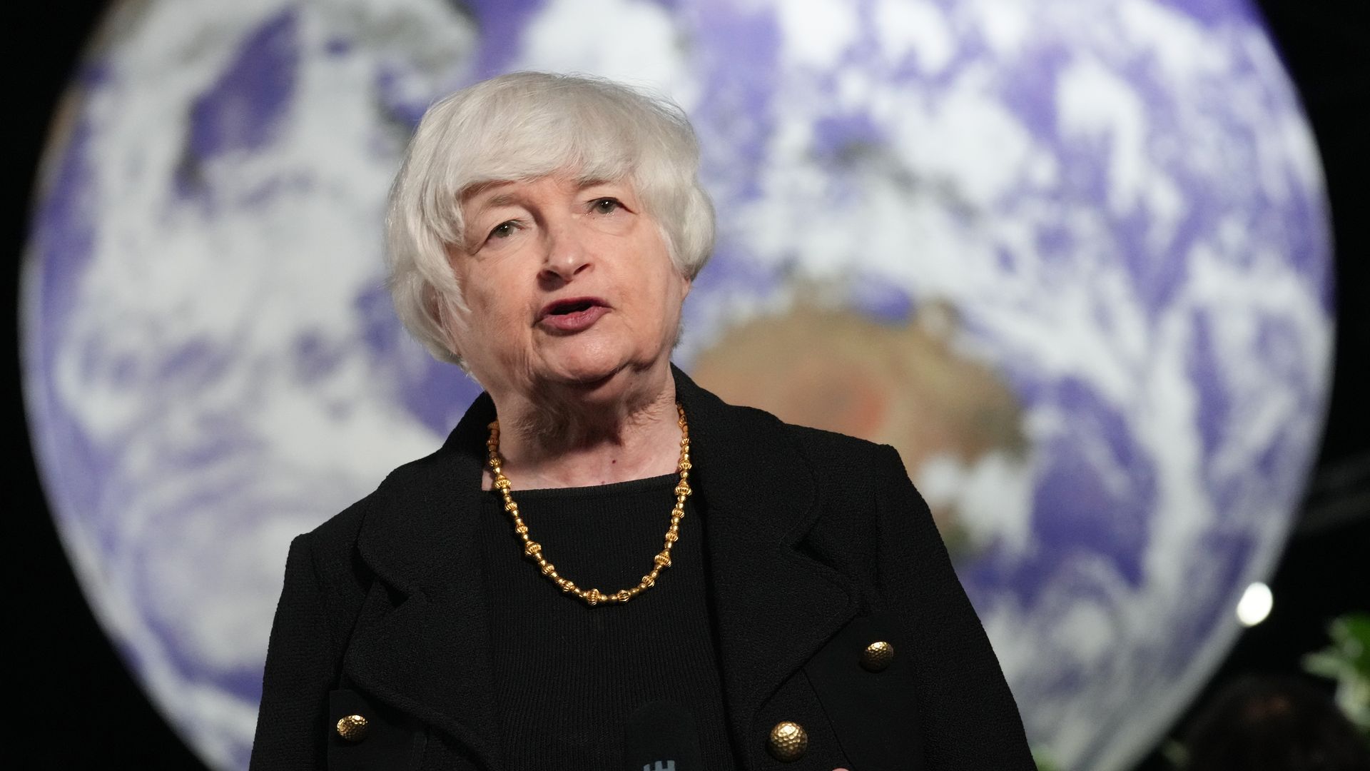 Photo of Janet Yellen speaking against the backdrop of the Earth's image