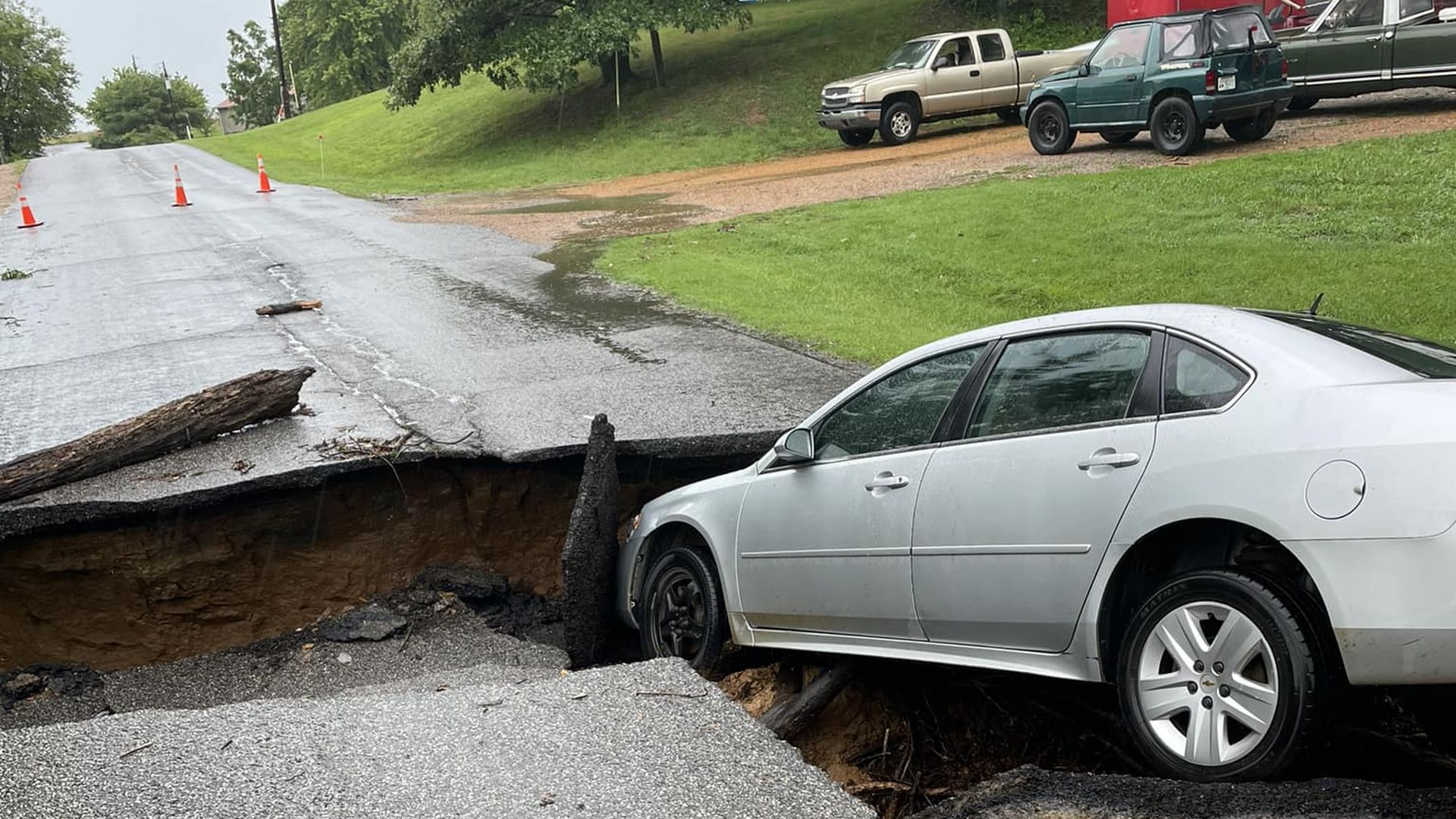 An image of a car stuck in a hole in the road caused by a washout in Mayfield, Kentucky.