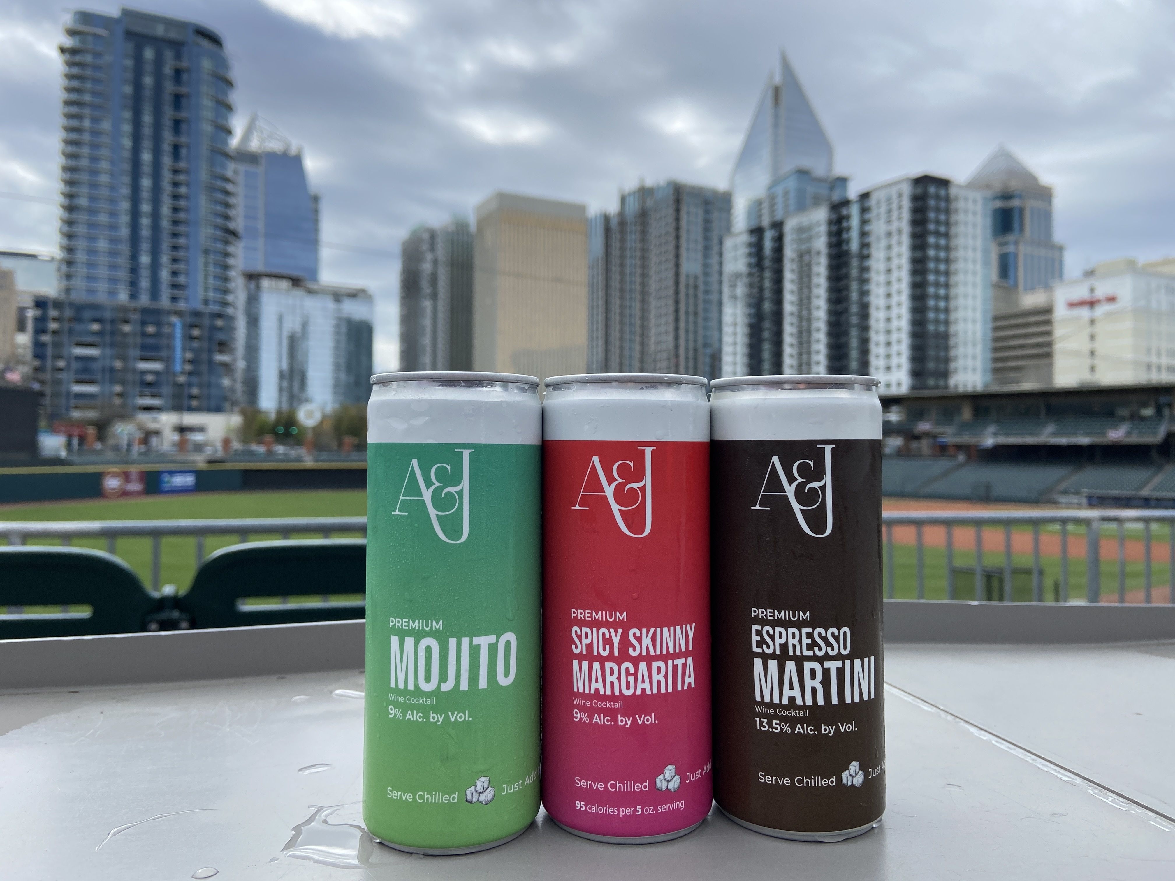 Cans of A&J Winery's cocktails at Truist Field with the Charlotte skyline in the background.
