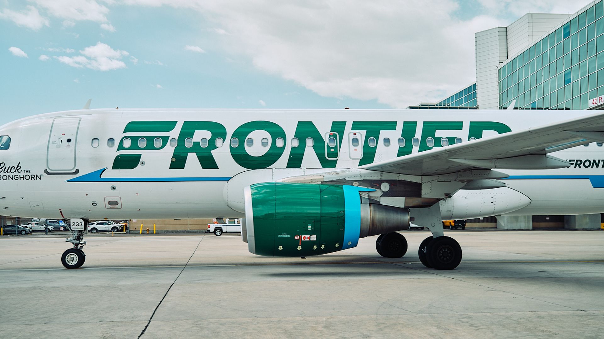 A Frontier Airlines plane from the side at an airport bay
