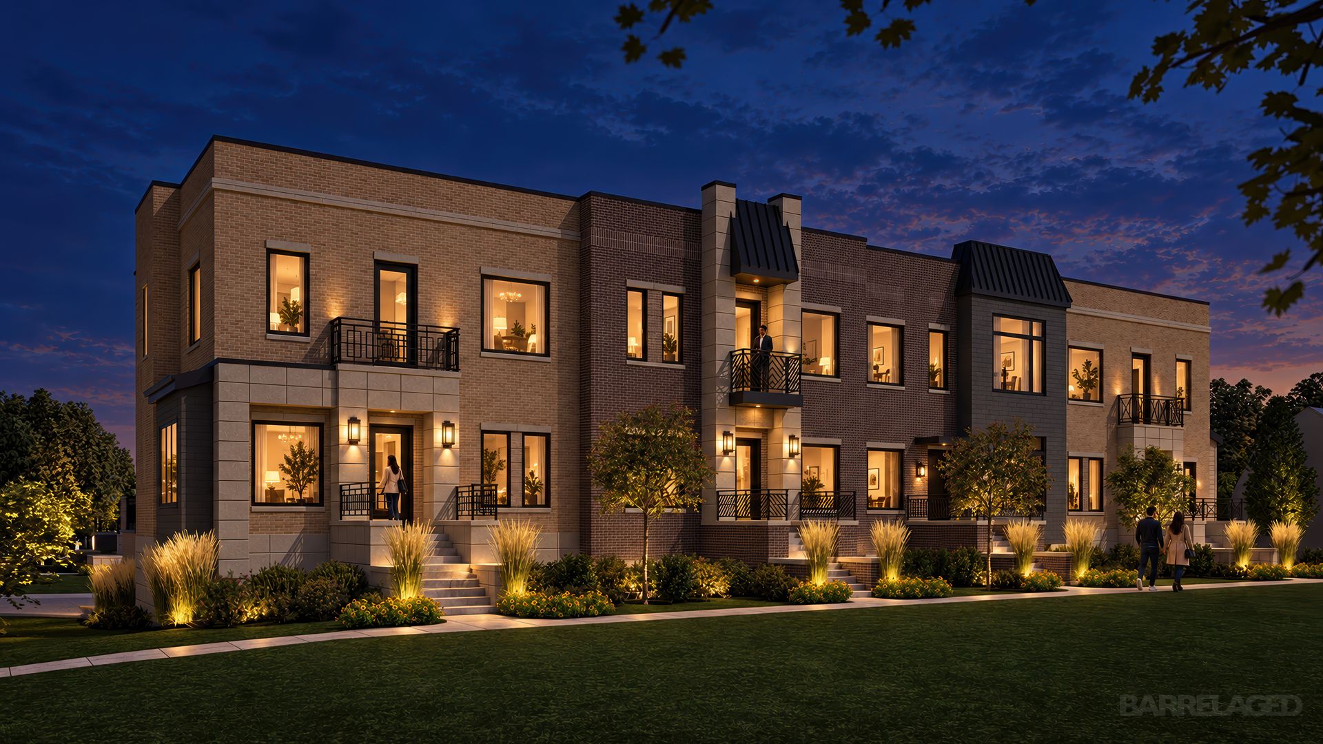 Evening view of a modern brick apartment building with warm interior lights, multiple windows and balconies, with a few people near the entrance, surrounded by illuminated landscaping and a dusk sky.