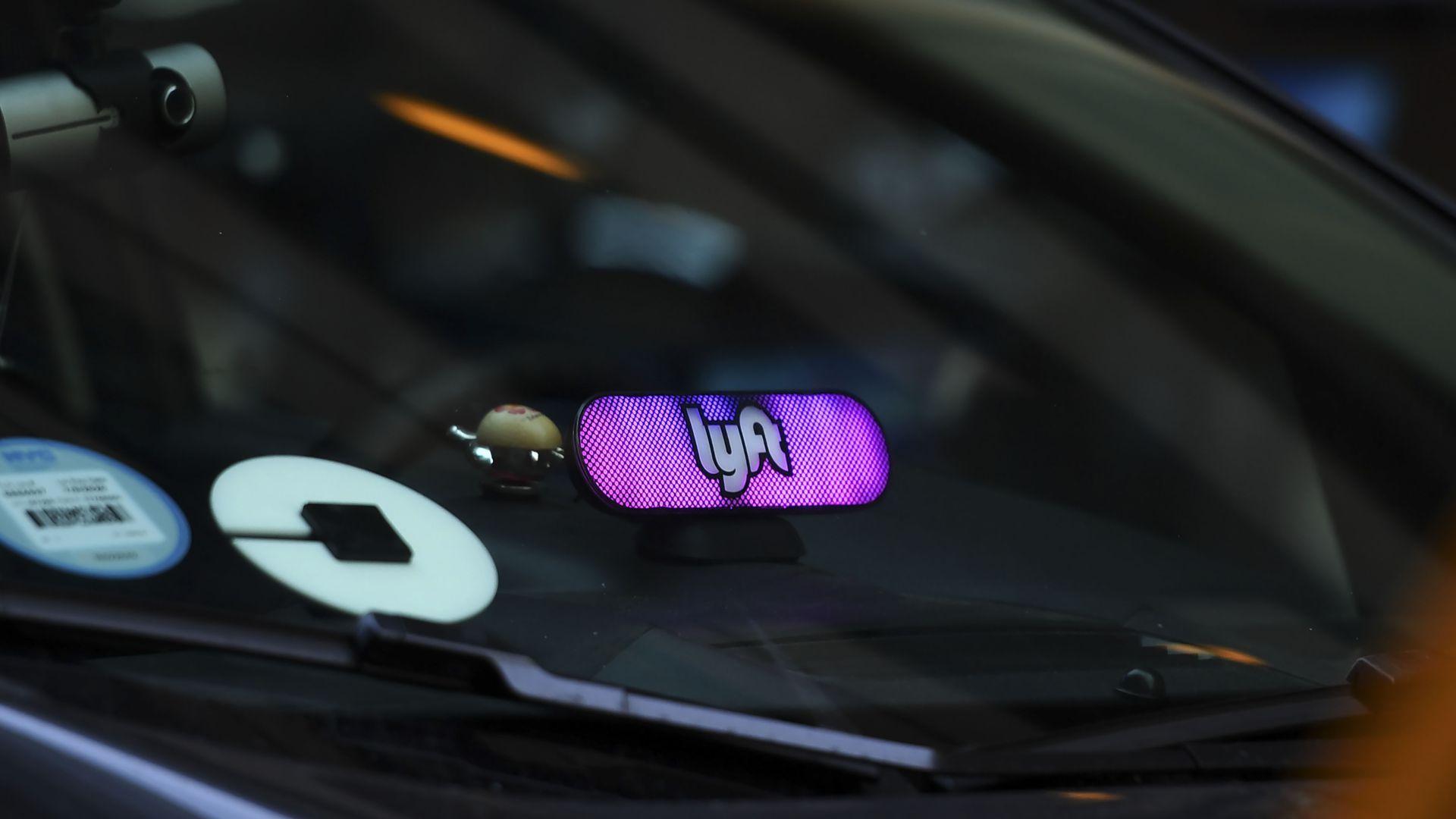 A car with both Lyft and Uber logos in the window