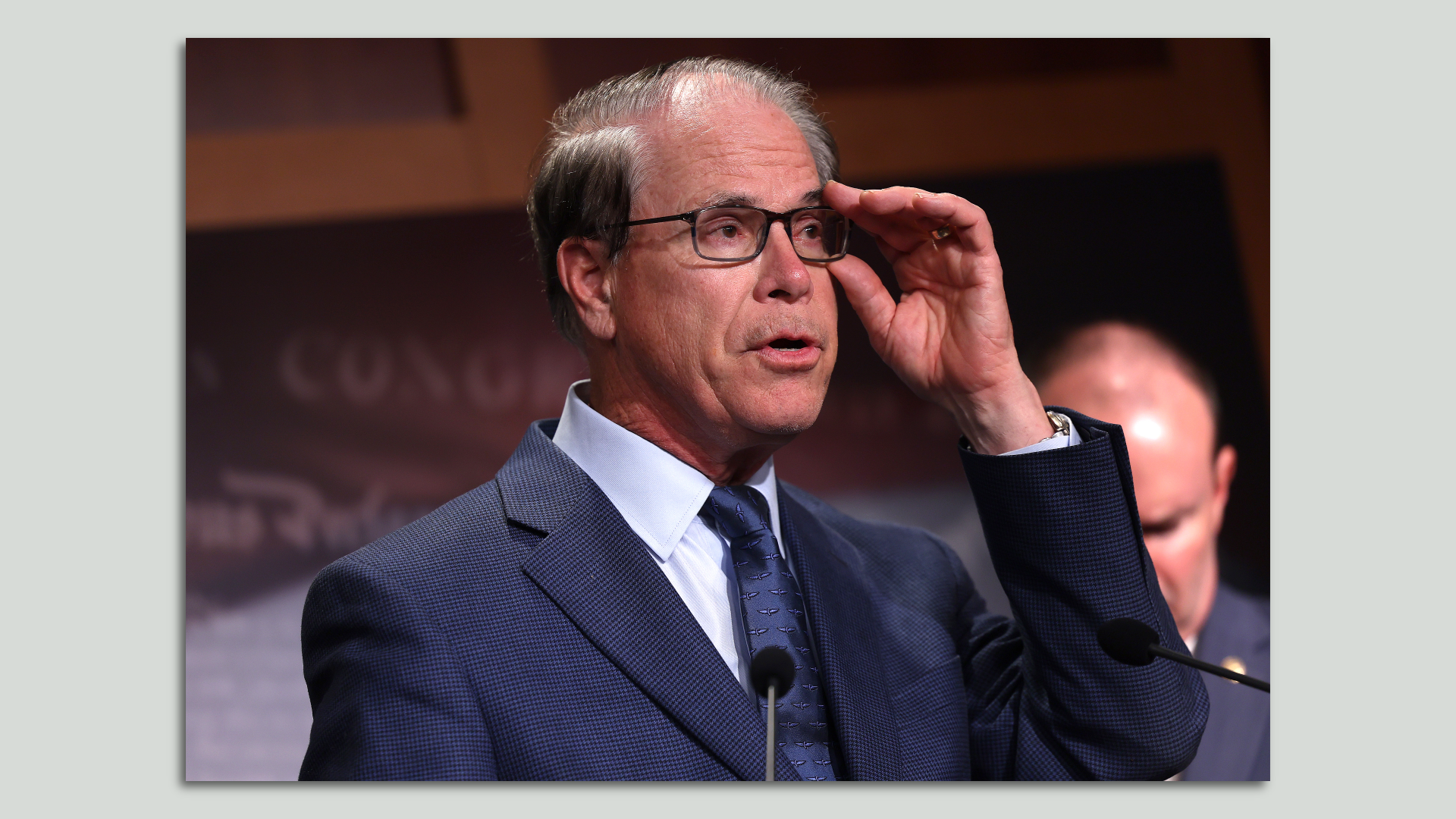 U.S. Sen Mike Braun in a blue suit touching his glasses