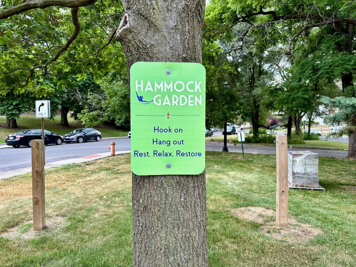 A sign on a tree reads "Hammock Garden, Hook On Hang Out Rest. Relax. Restore"