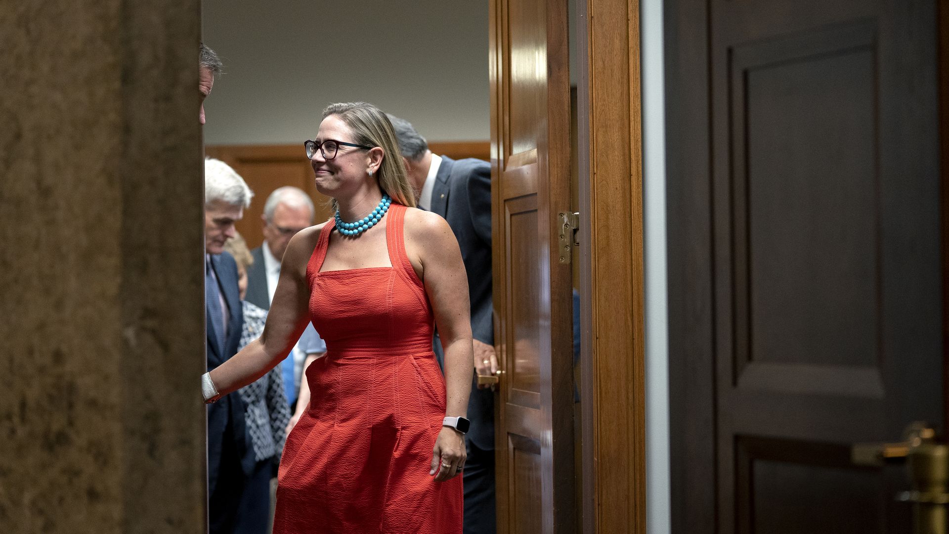 Sen. Kyrsten Sinema is seen shaking hands as she leaves a meeting of the bipartisan infrastructure group.