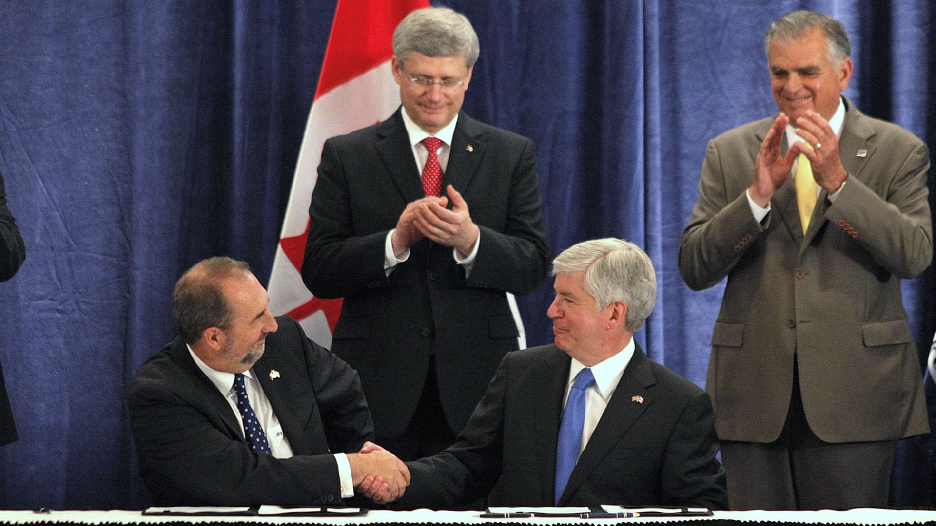 Pictured in 2012, then-Gov. Rick Snyder (second right) and Canada's minister of infrastructure (left) shake hands in Detroit after signing an agreement to build the new international crossing. 