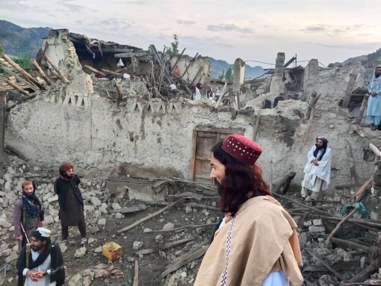 In this photo released by a state-run news agency Bakhtar, Afghans look at destruction caused by an earthquake in the province of Paktika, eastern Afghanistan, Wednesday, June 22,