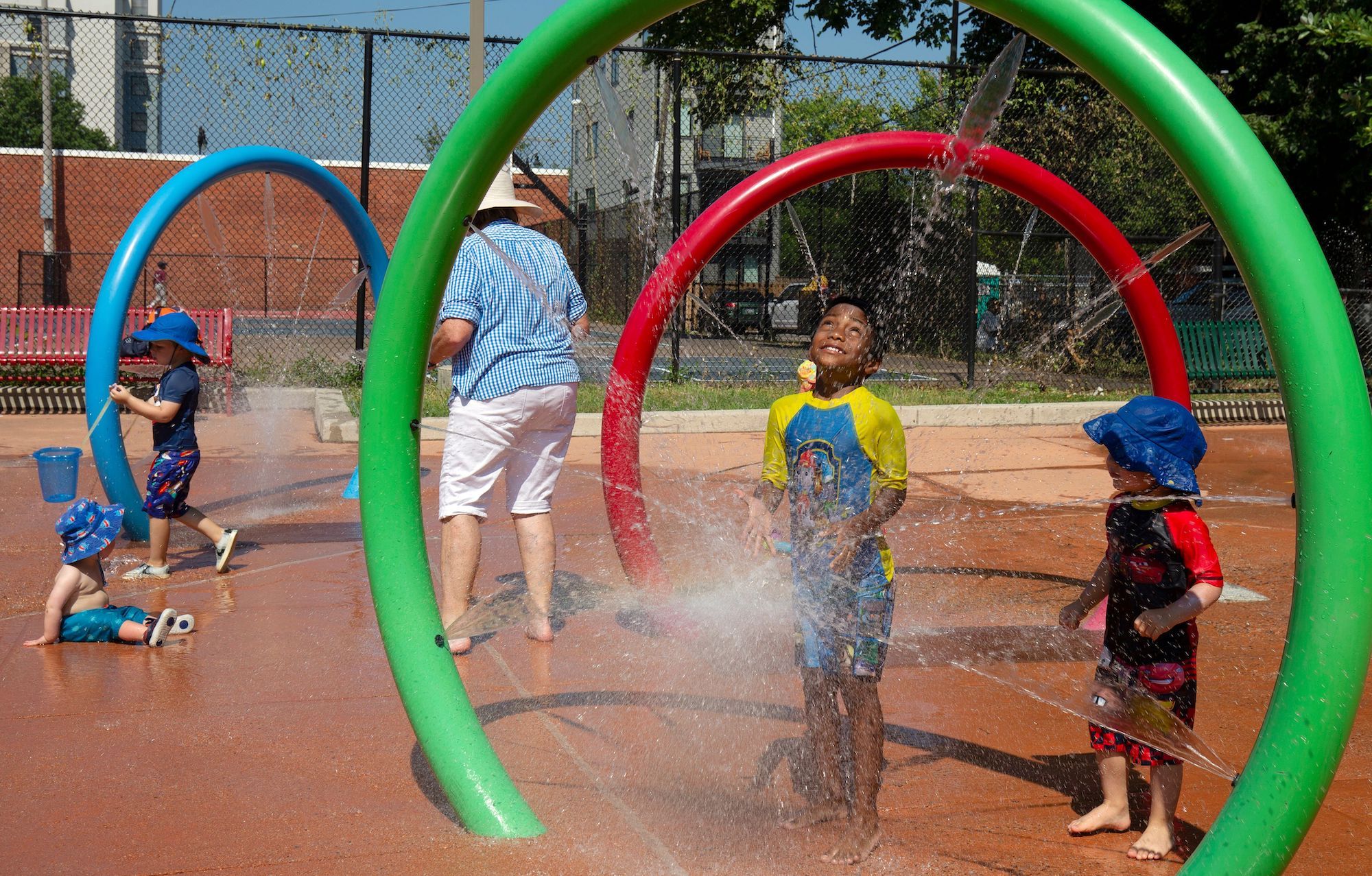 Children cool down at the Petworth Spray Park in Washington, DC, on July 19, 2019. - Some 100 heat records are expected to fall this weekend, according to the National Weather Service, as a heat wave hits the midwest and eastern US. (Photo by Alastair Pike / AFP) (Photo credit should read ALASTAIR P