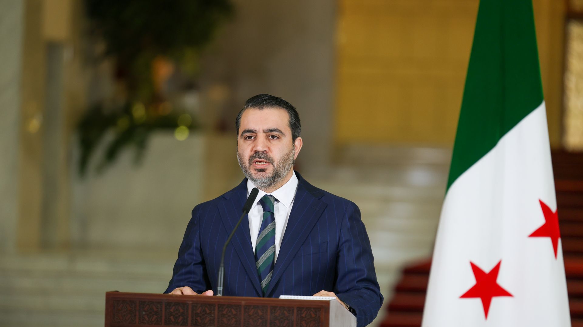 Syrian Foreign Minister Asaad al-Shaibani stands at a lectern during a 2025 press conference.