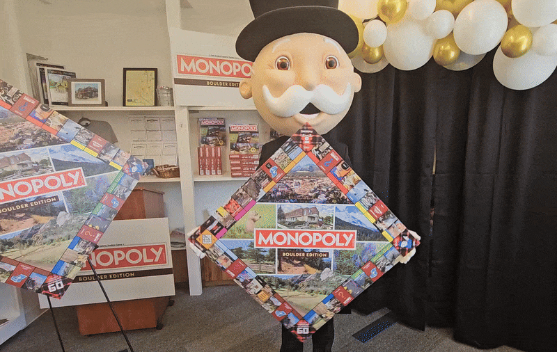 A person in a Mr. Monopoly costume holds the new Monopoly: Boulder edition game.