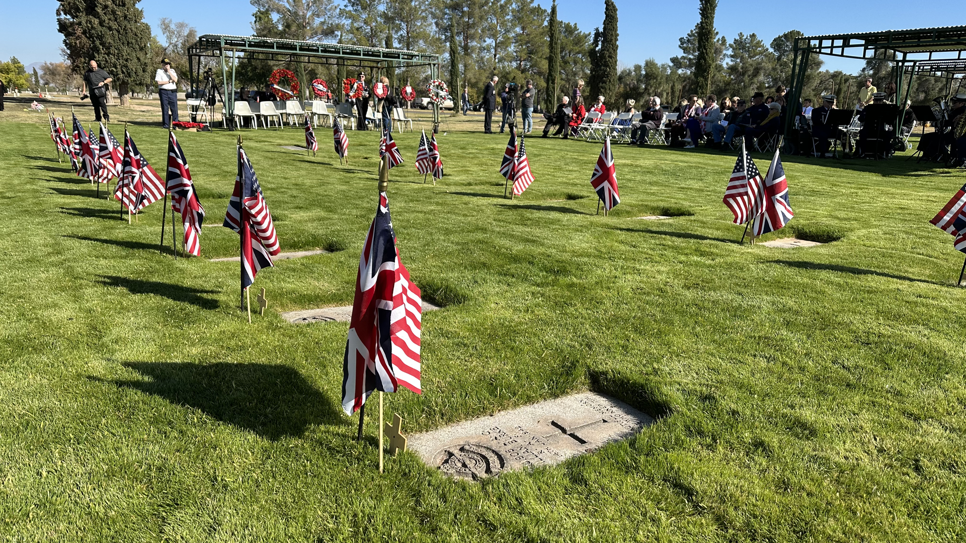 American and UK flags in front of several gravestones.