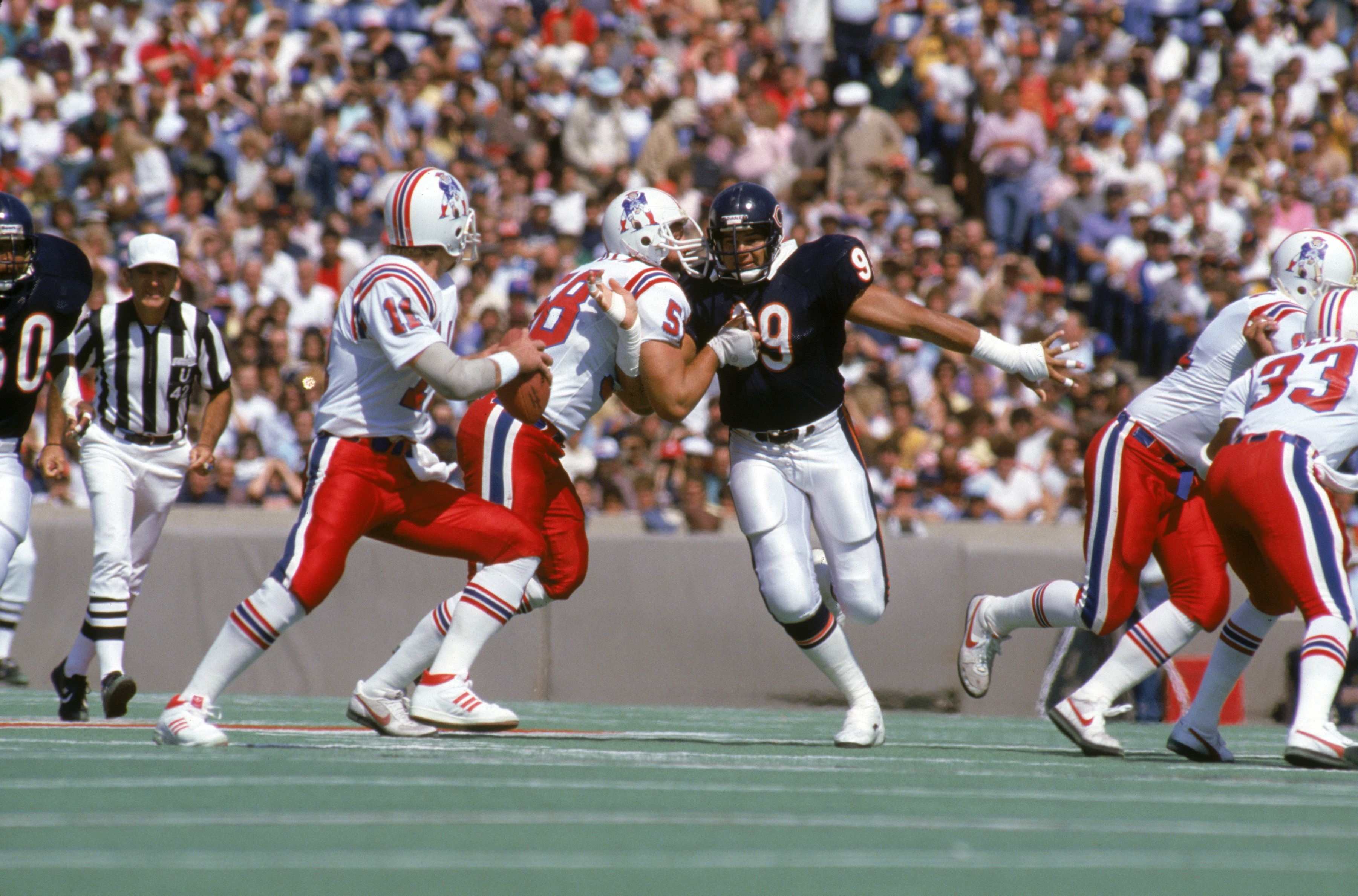Football players on the field playing a game in front of a crowd. 