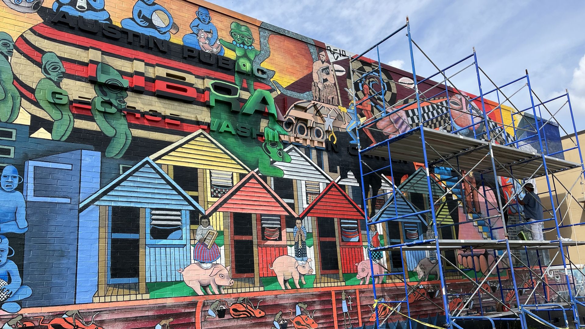 John Fisher refreshing his East Austin mural.