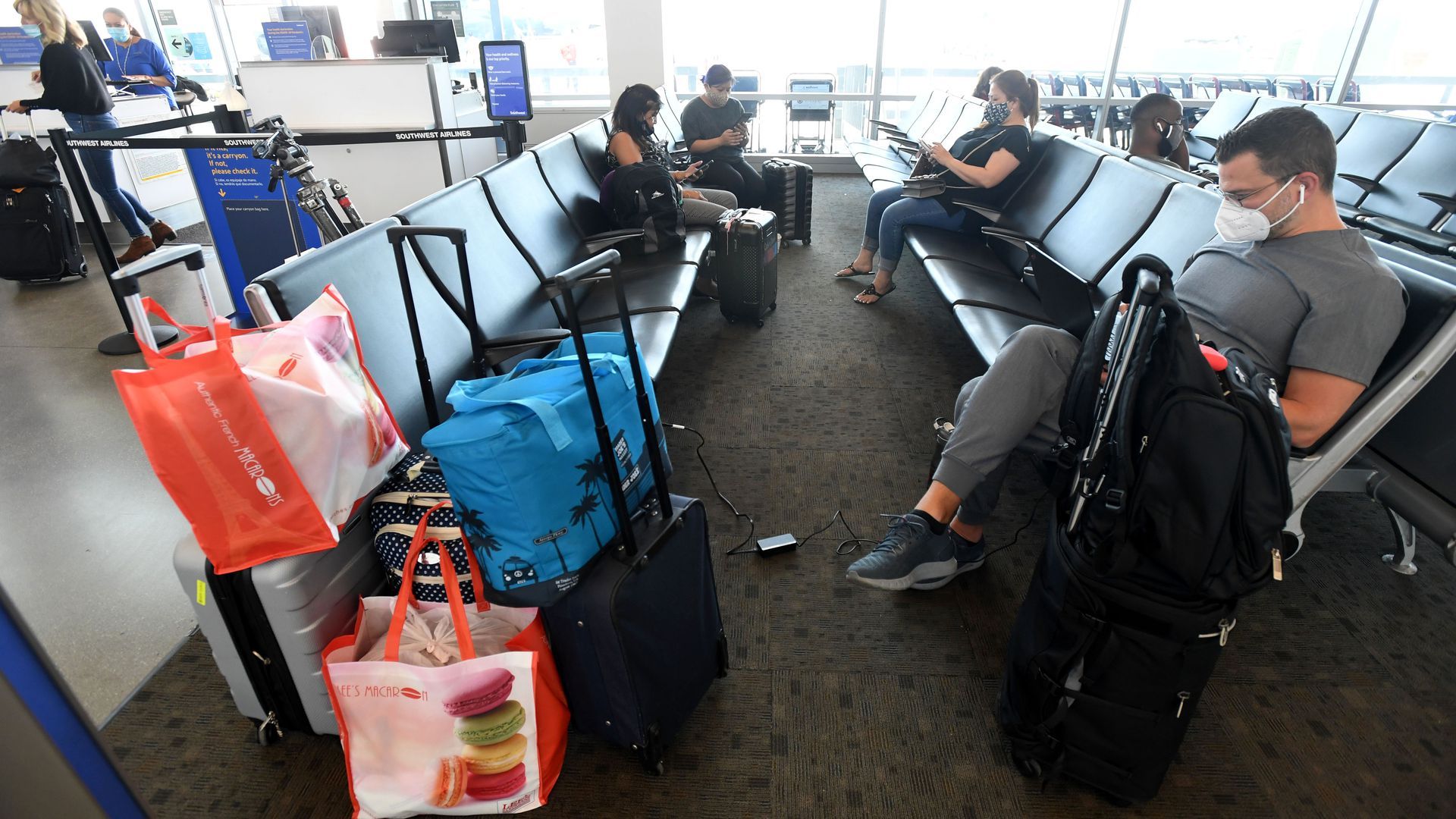 airport gate with travelers wearing masks