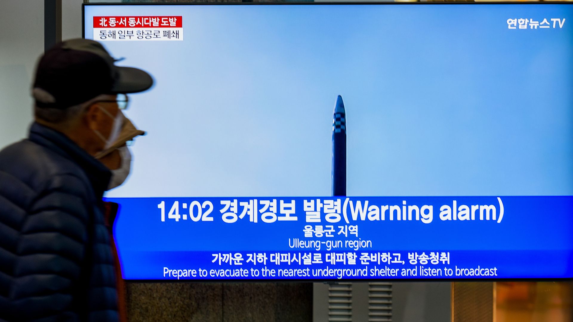 People watch a news broadcast flashing a warning alarm after a North Korean missle launch 
