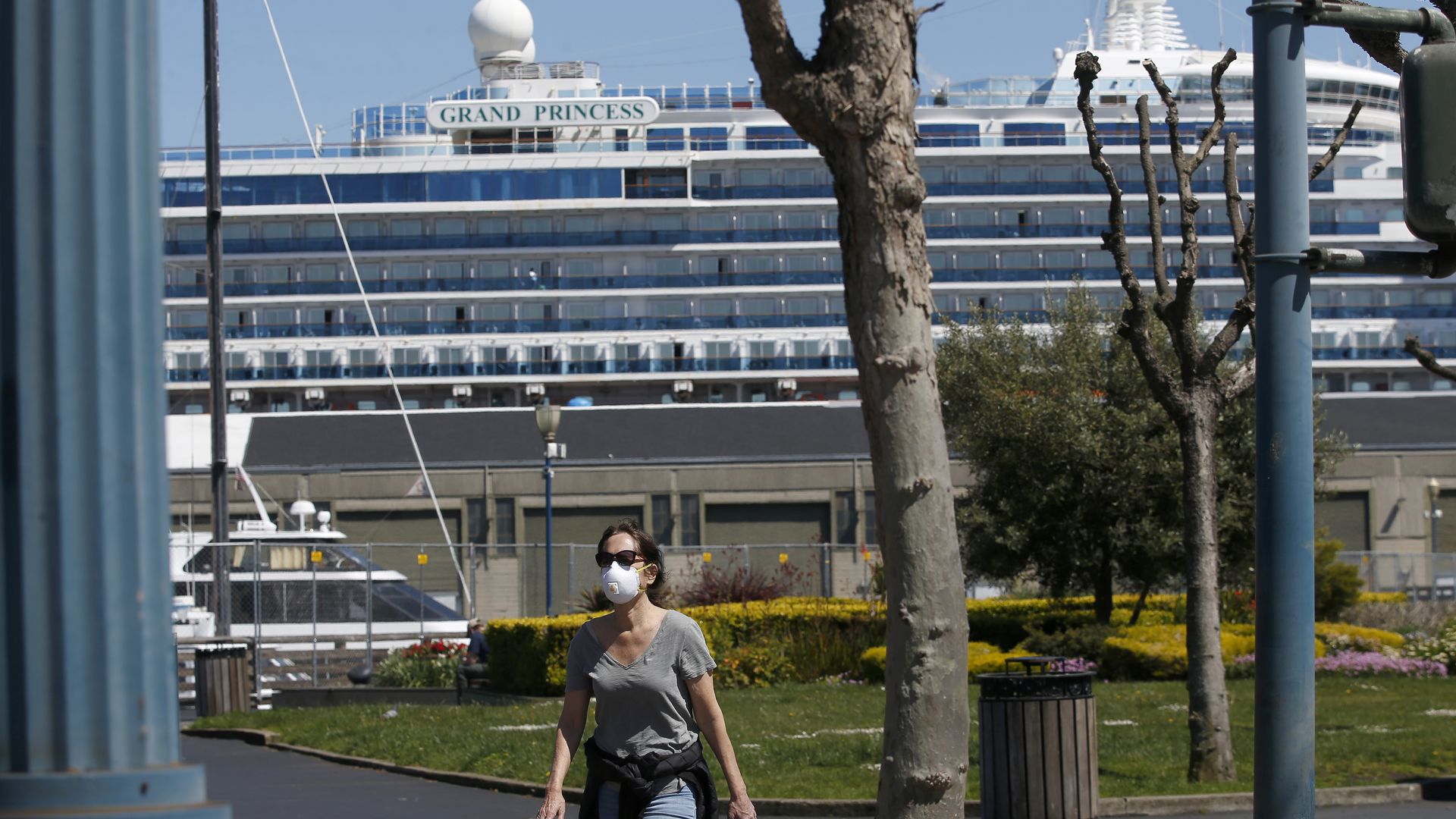 A woman with a mask walks past as the coronavirus-stricken Grand Princess cruise ship