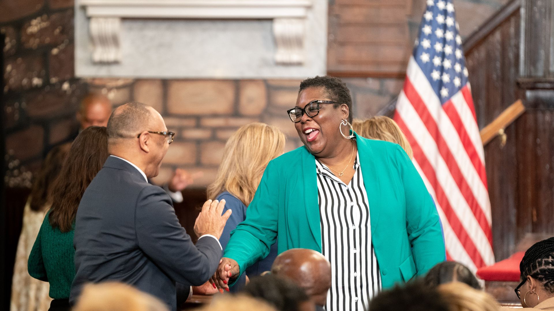 South Carolina Democratic Party chair Christale Spain shakes a man's hand with a U.S. flag in the background.