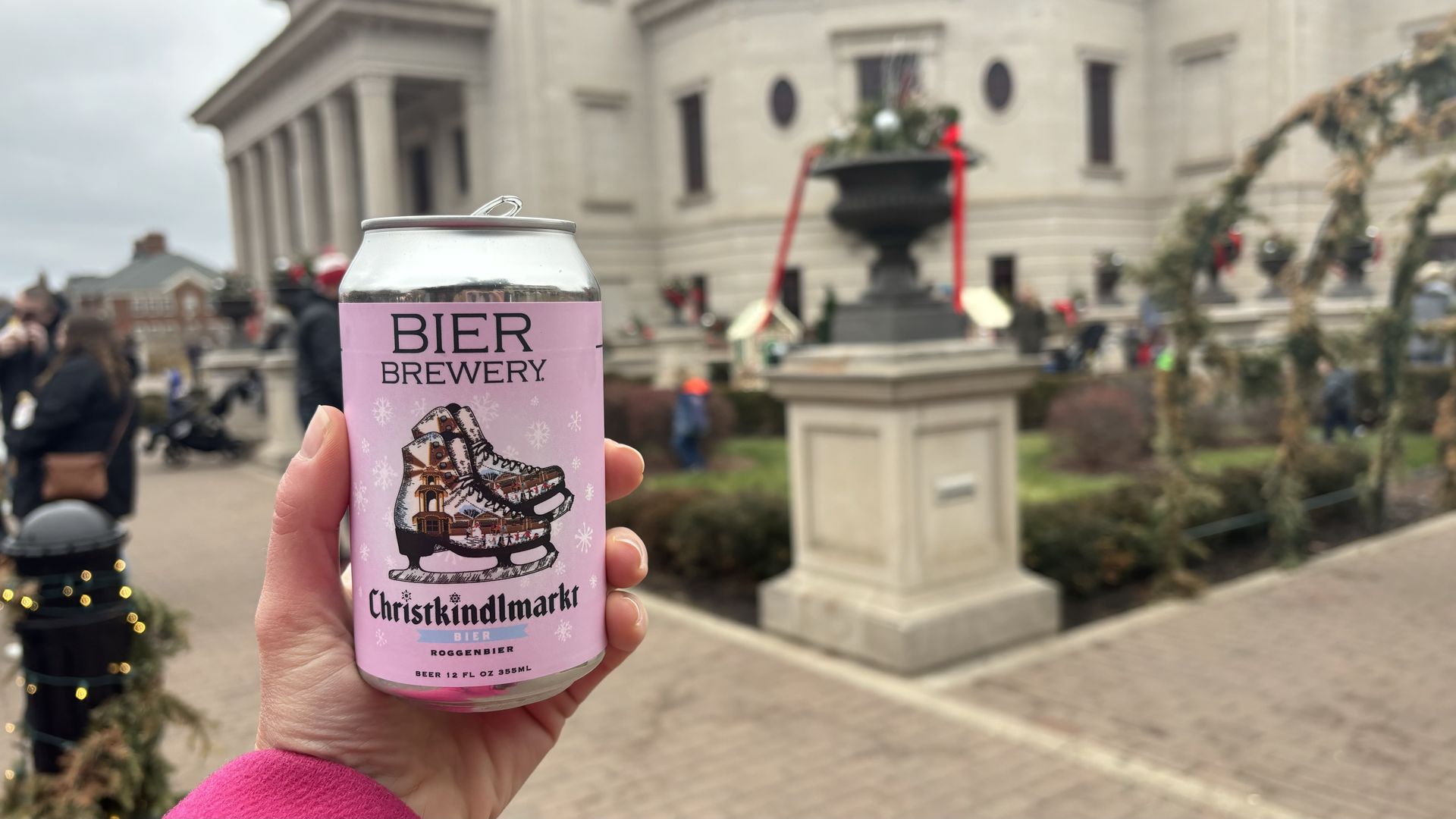 A hand holding a pink beer can