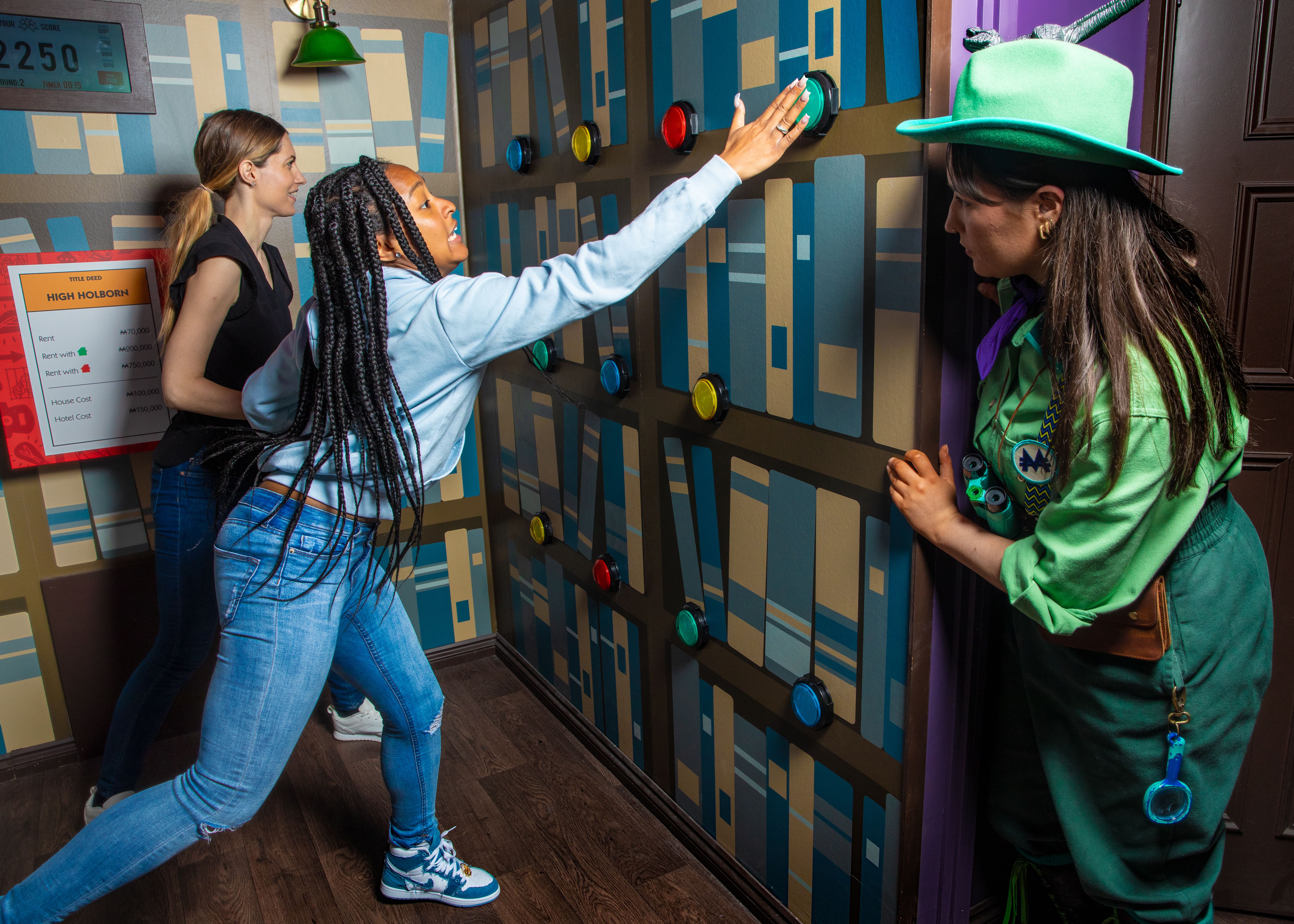 A girl hits a button on the wall during a game of lifesize Monopoly
