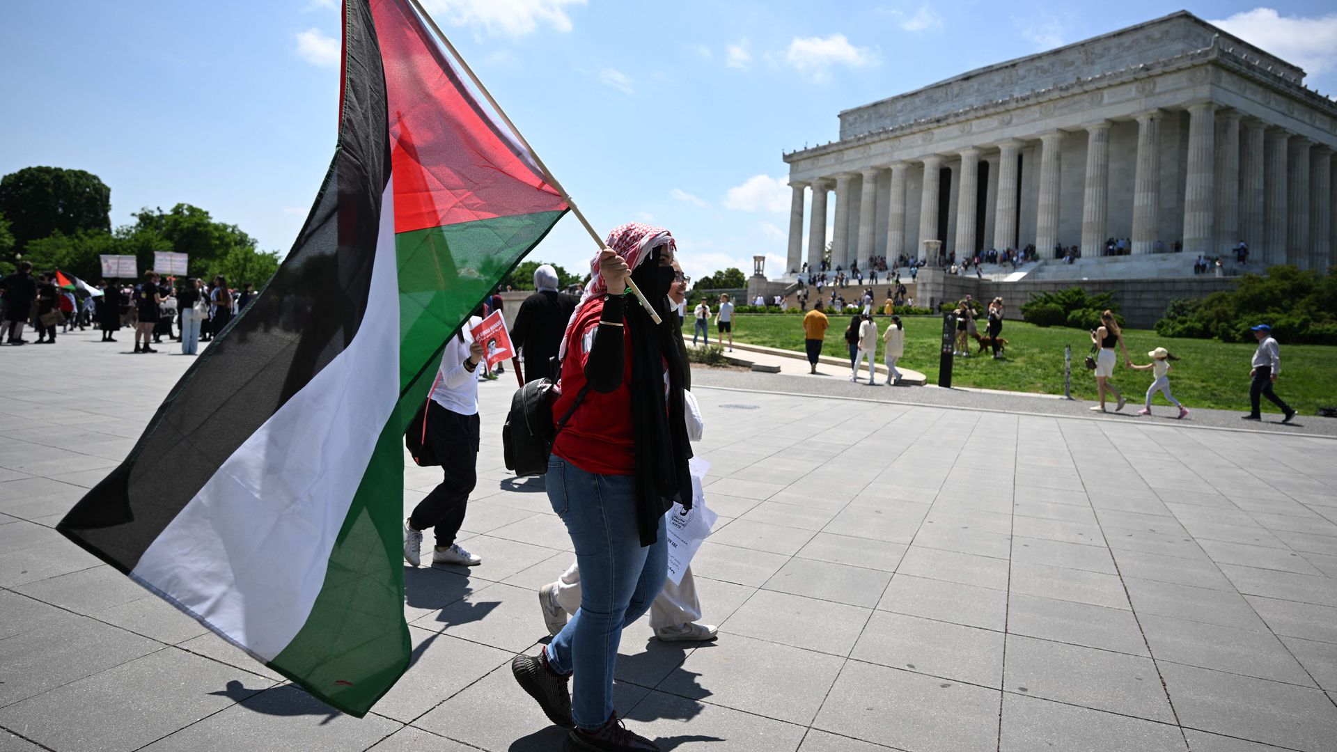 A pro-Palestinian activist is seen carrying a flag near the Lincoln Memorial.