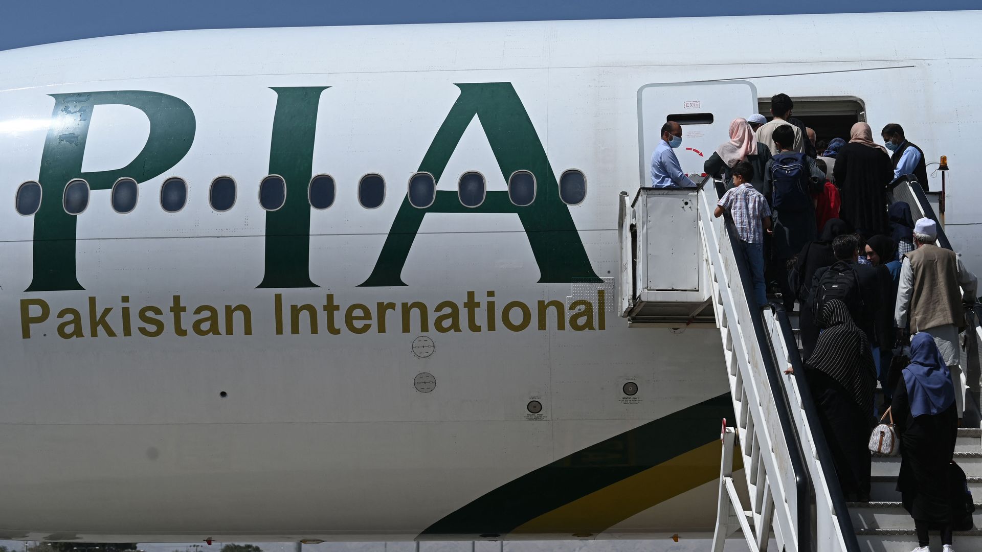 Passengers board a Pakistan International Airlines (PIA) flight, the first commercial international flight since the Taliban retook power last month, at the airport in Kabul on September 13, 2021. (