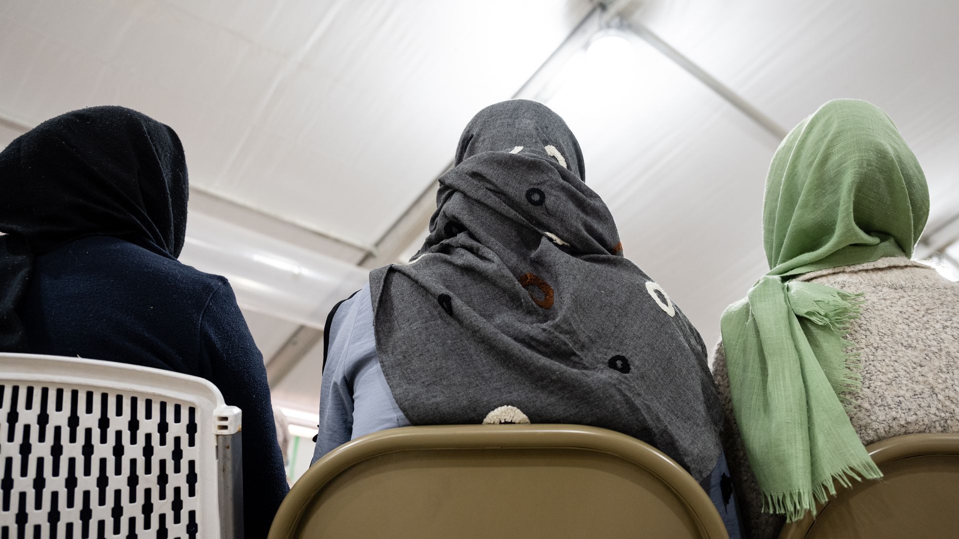 Three women watch as a lesson is taught in the education center of an Afghan refugee camp in New Mexico