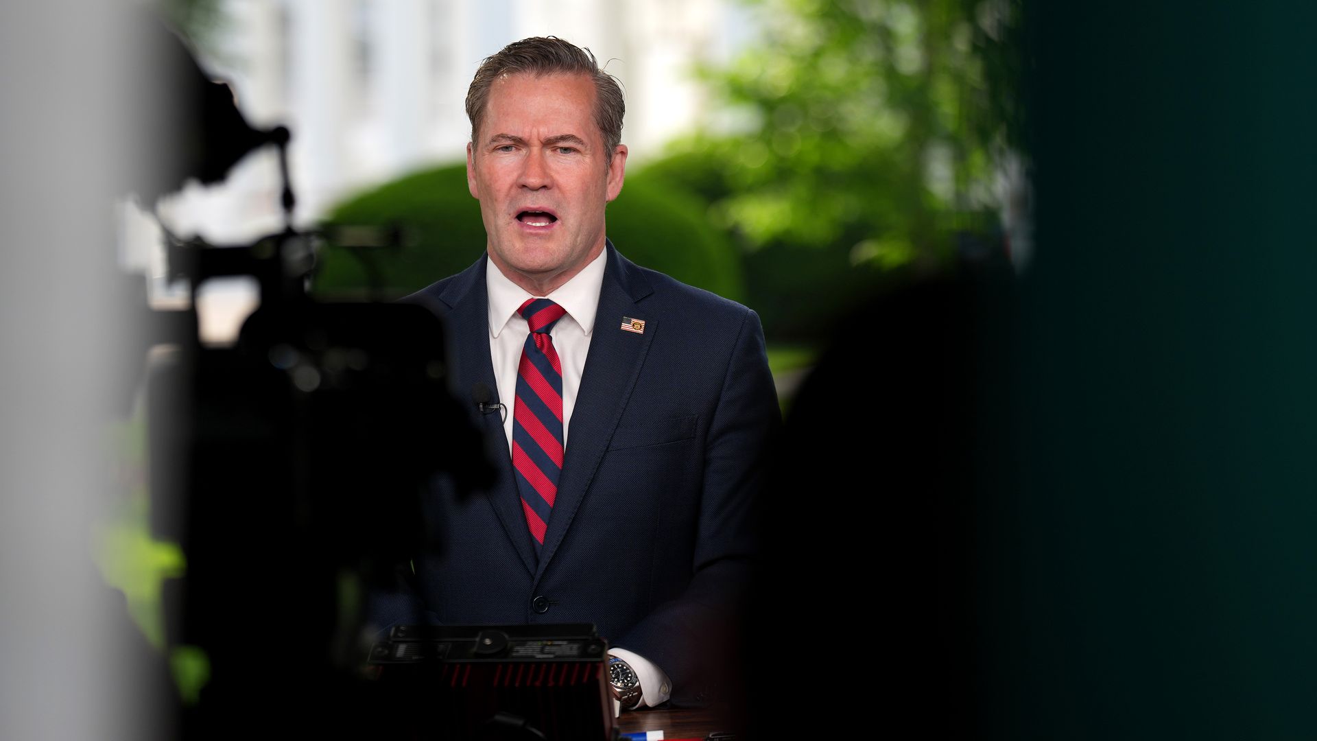 National security advisor Mike Waltz wearing a blue suit and speaking in front of the White House.