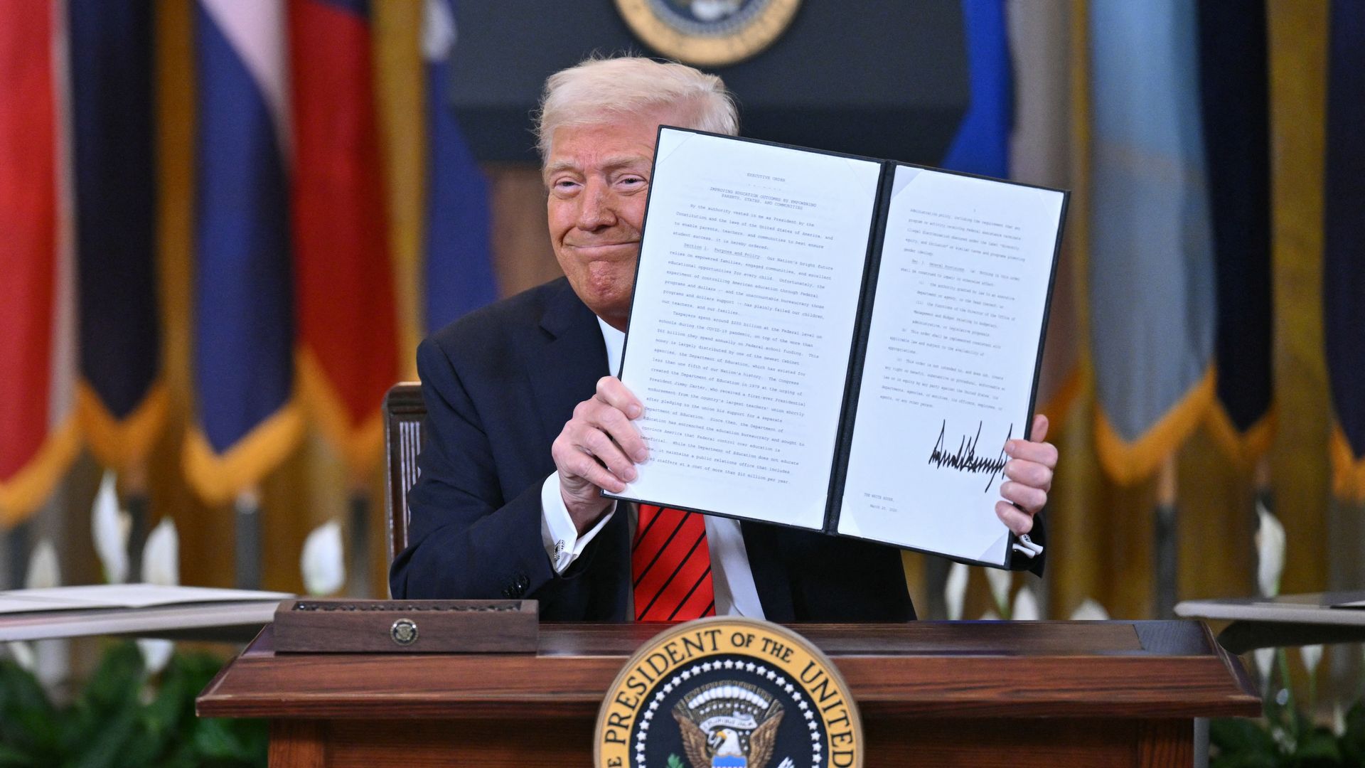 President Donald Trump holds up a signed executive order during a press event. 