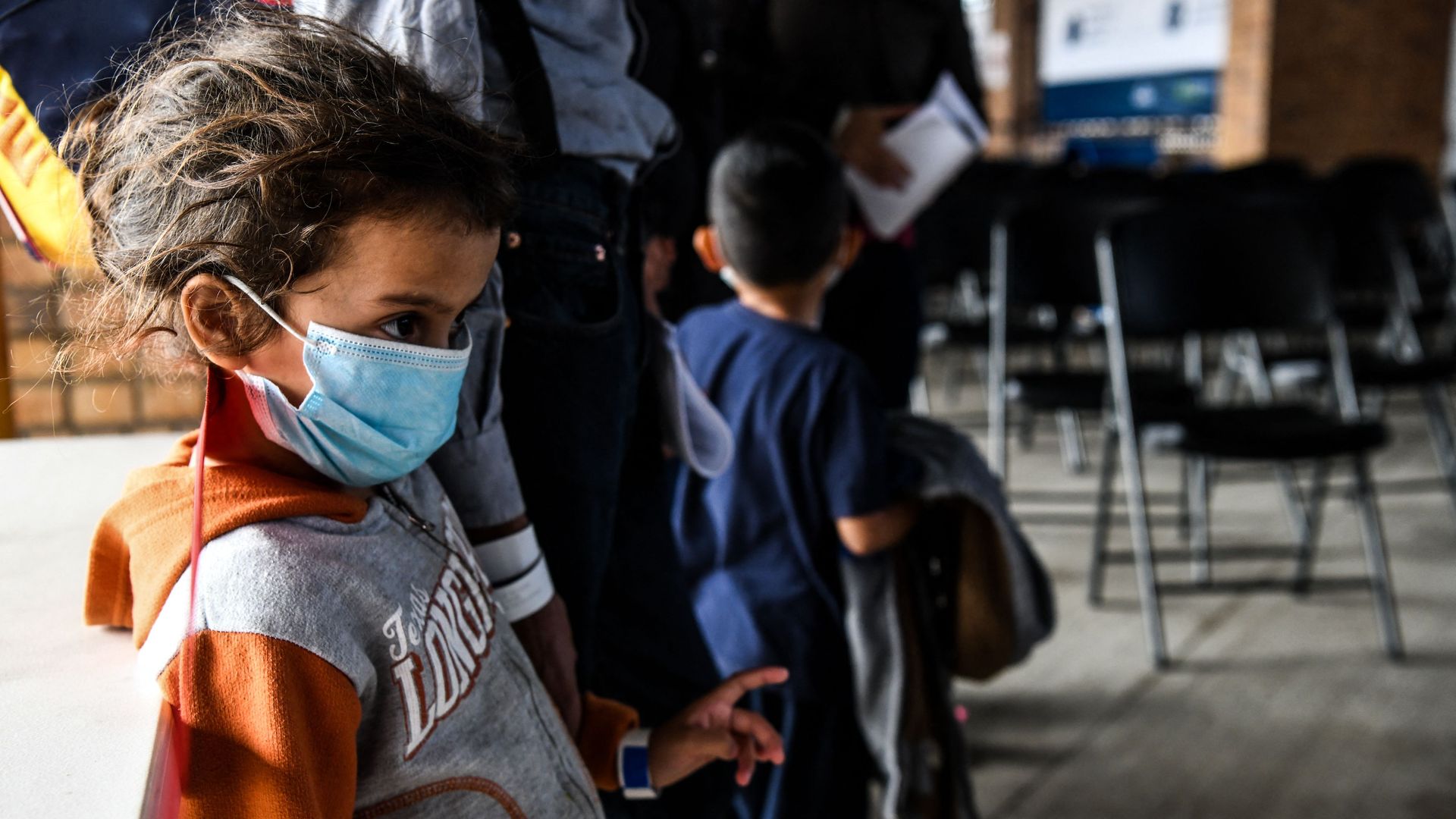 A migrant girl from Central America waits with her mother for a bus after they are dropped off by the US Customs and Border Protection at a bus station near the Gateway International Bridge