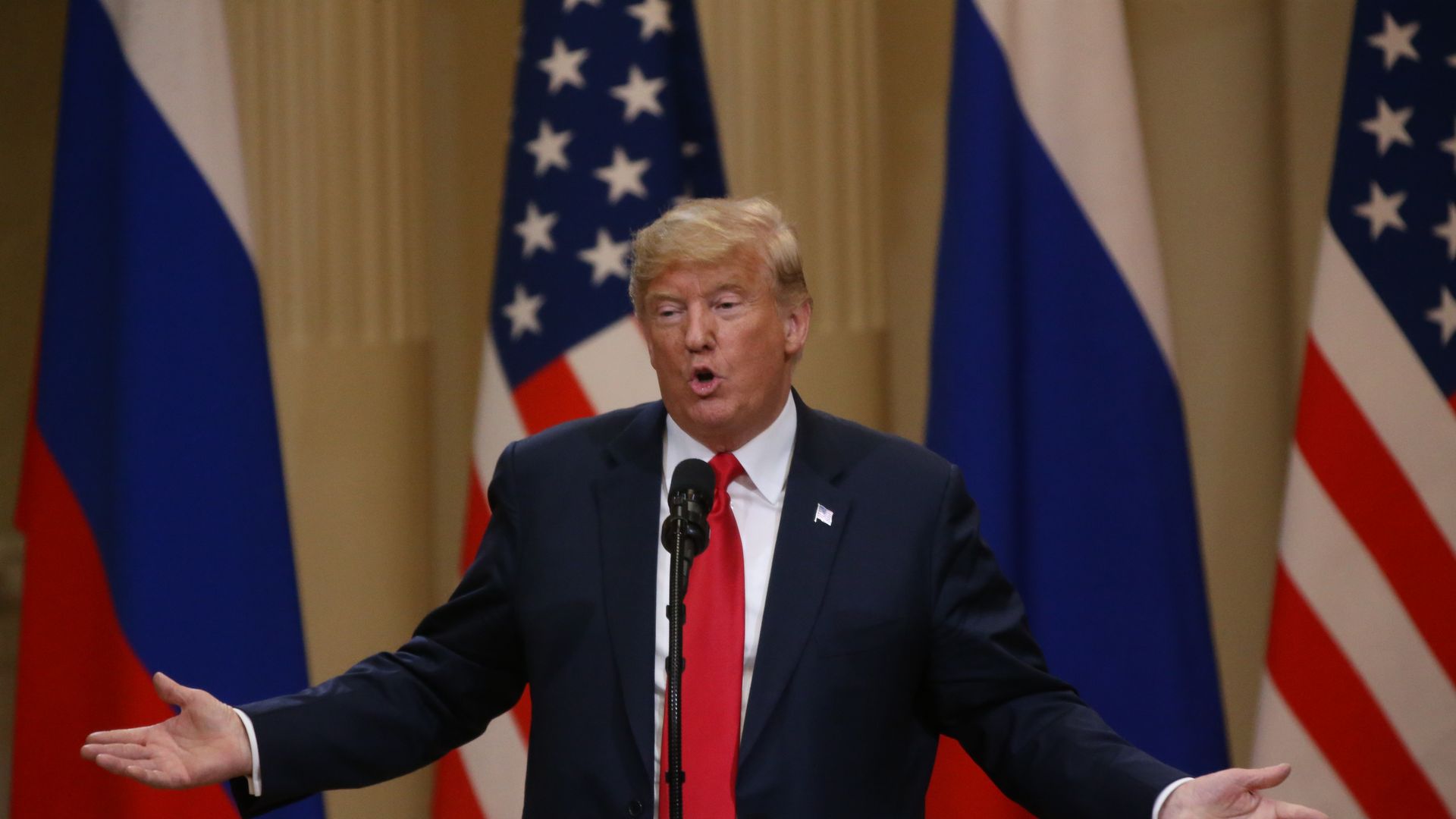 Donald Trump speaks while opening both his arms to the sides in a shrug