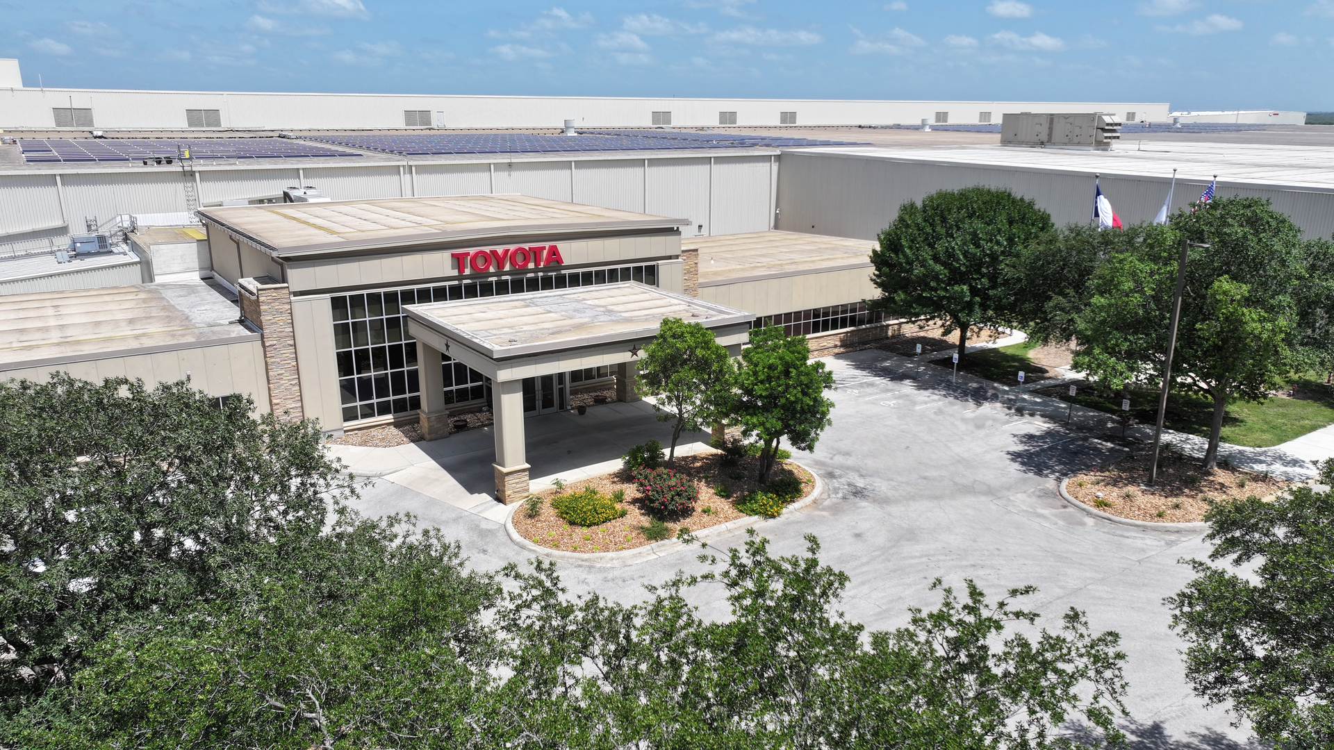 Aerial view of a large building with a Toyota sign on top with warehouses connected.