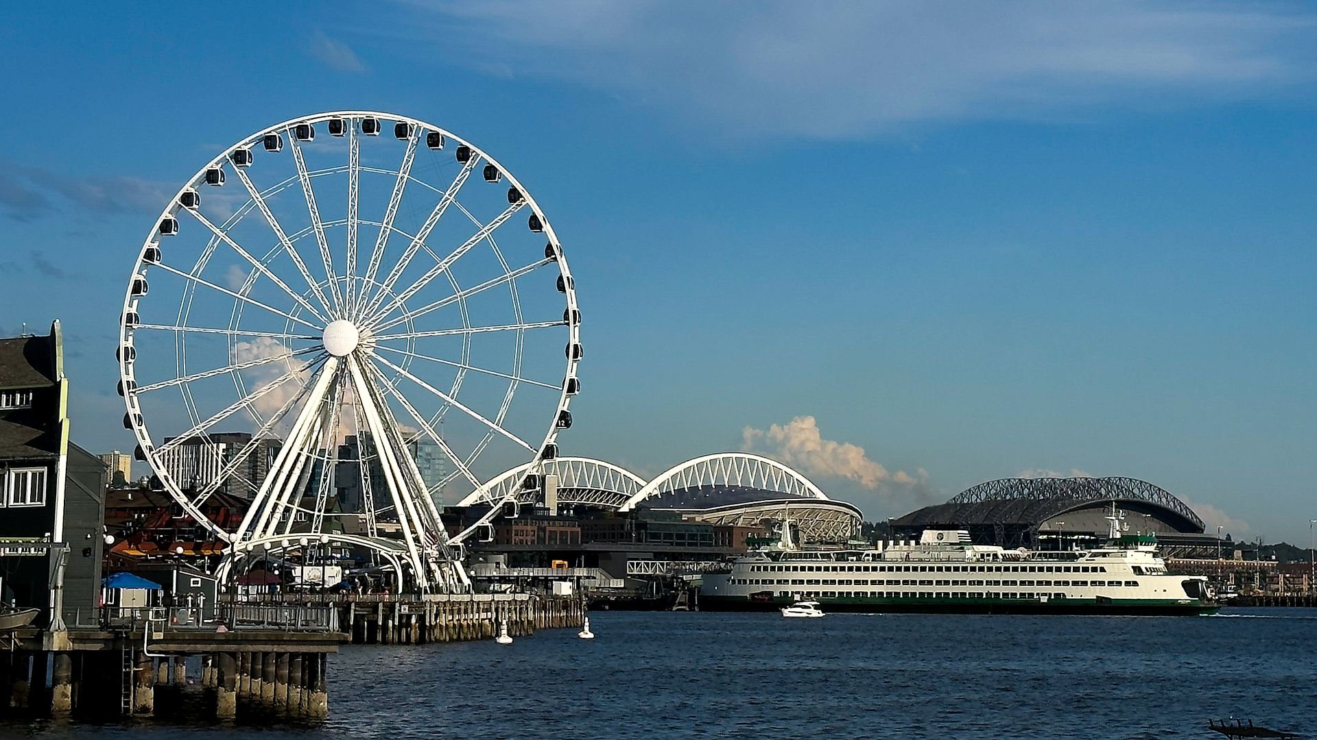 A view of Seattle with the ferris wheel in the foreground and the stadiums in the back.