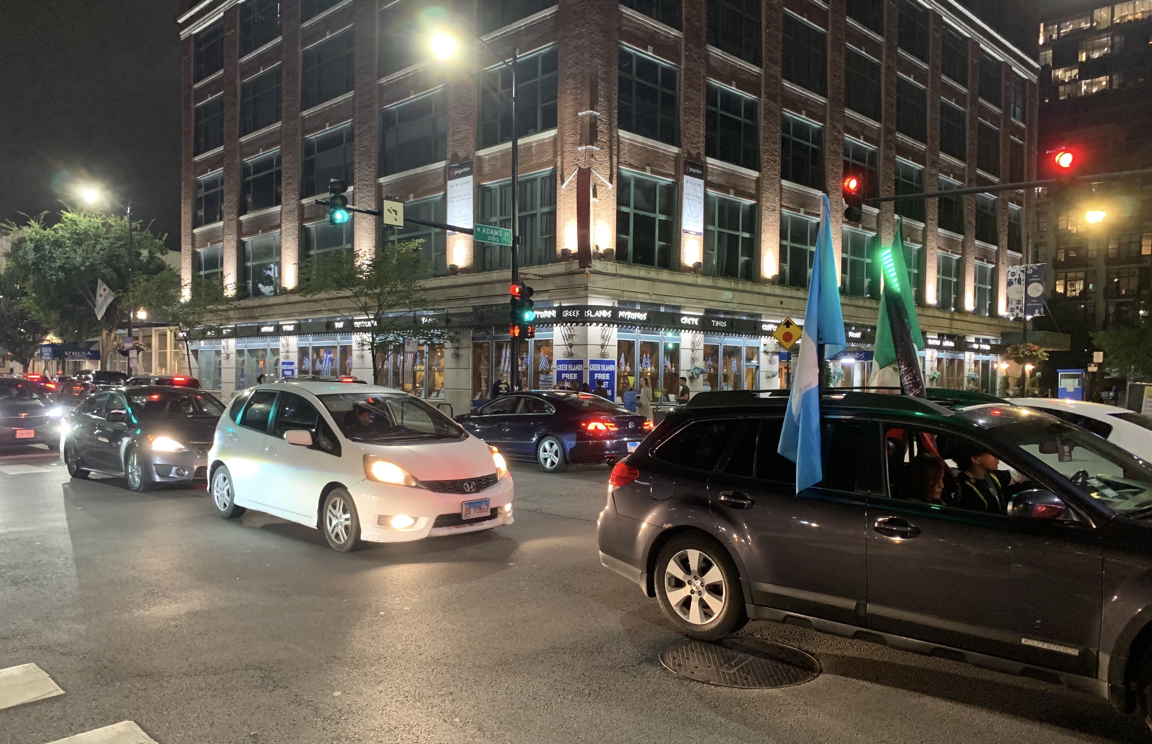 Cars in traffic, one with flags attached.