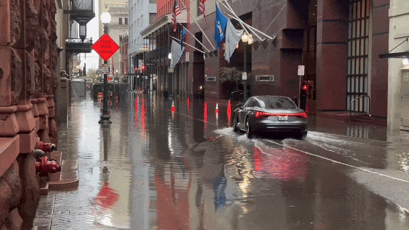 Image shows a car driving on a flooded street in New Orleans.