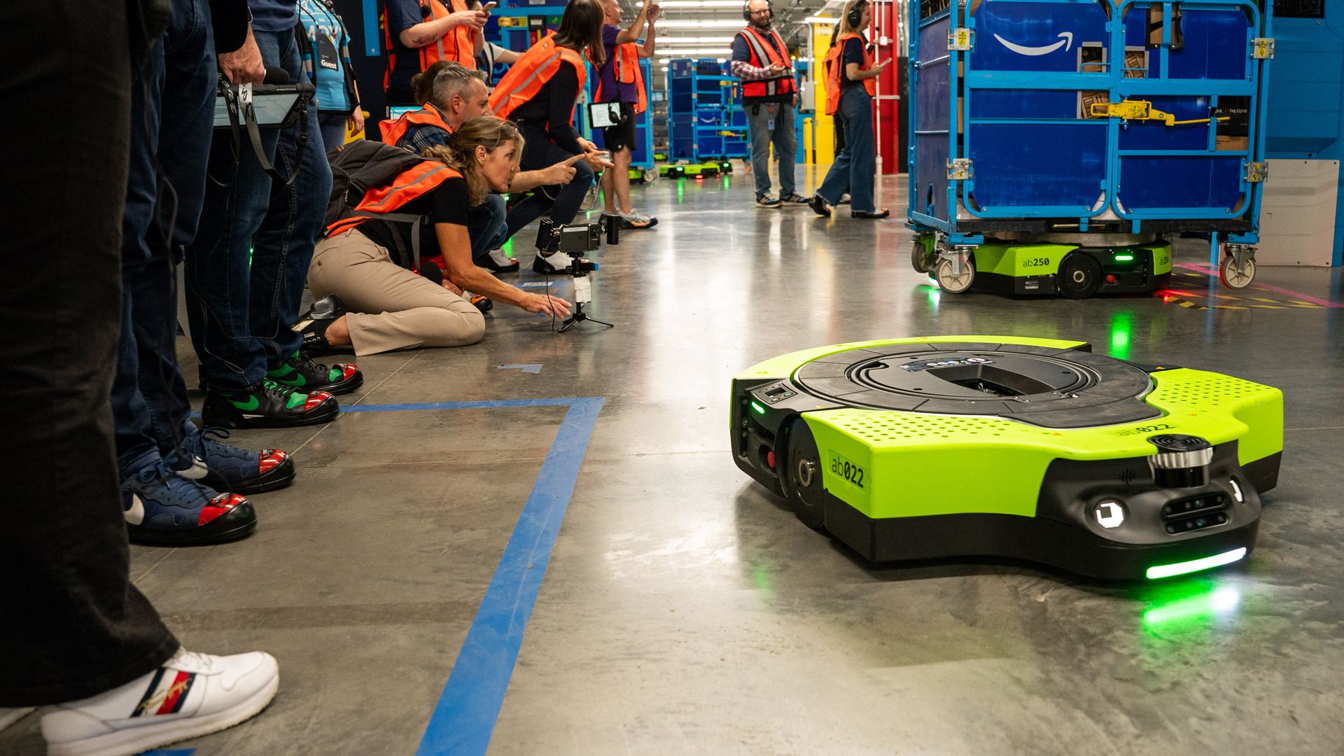 Workers interacting with a robot in a warehouse.