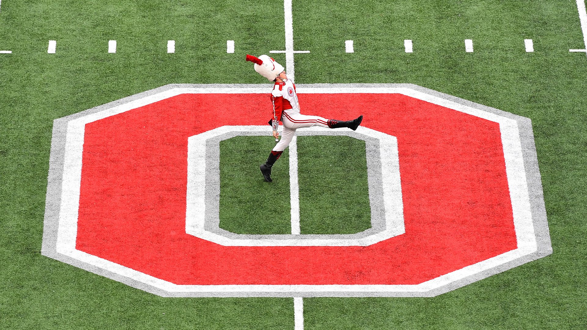 An Ohio State marching band drum major marches across the field. 
