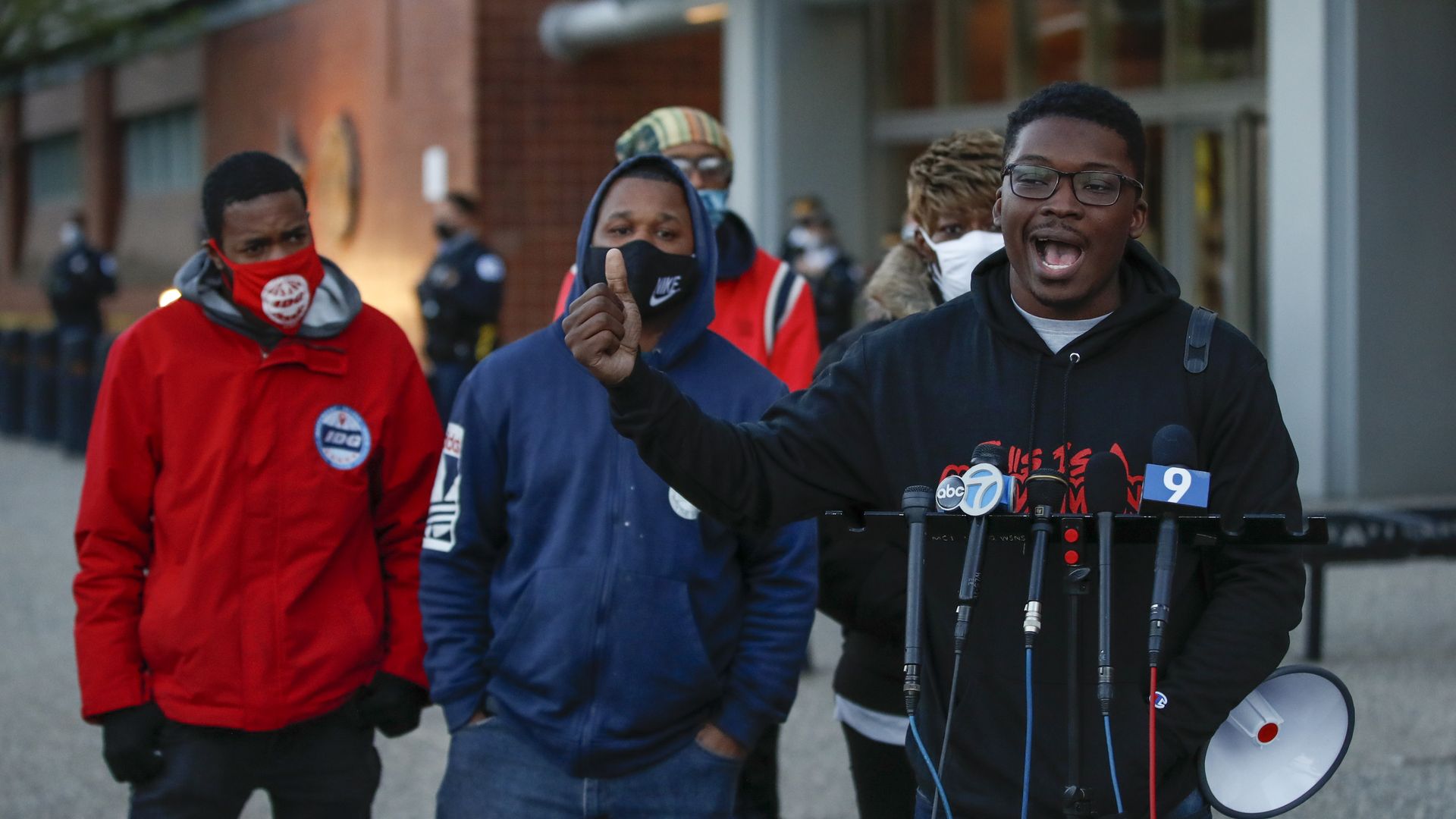 Photo of a man speaking into a microphone during a press conference. 