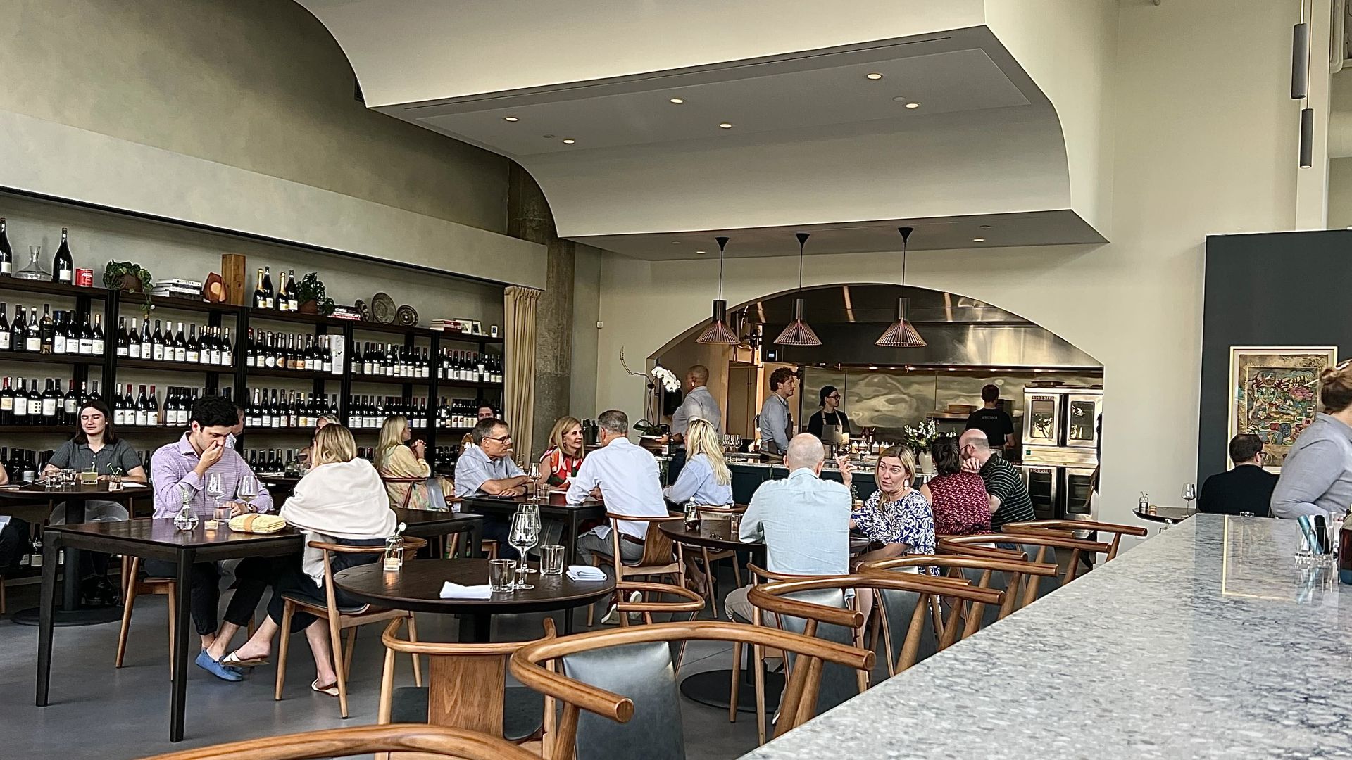 inside restaurant with wall full of wine and several diners in the center