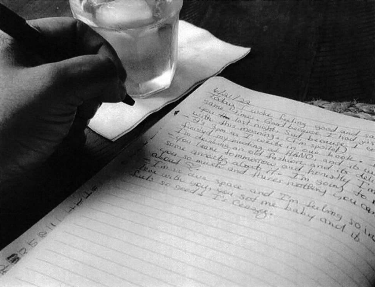 Photo shows someone writing a love note in a book.