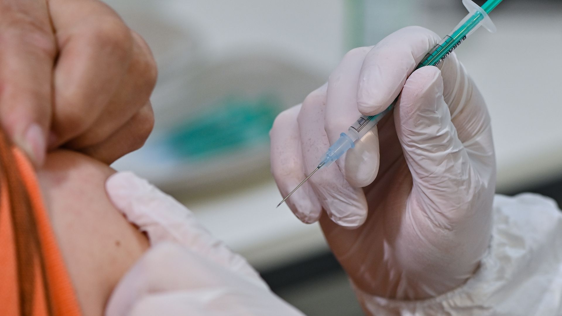 A provider prepares to deliver a shot into an arm.