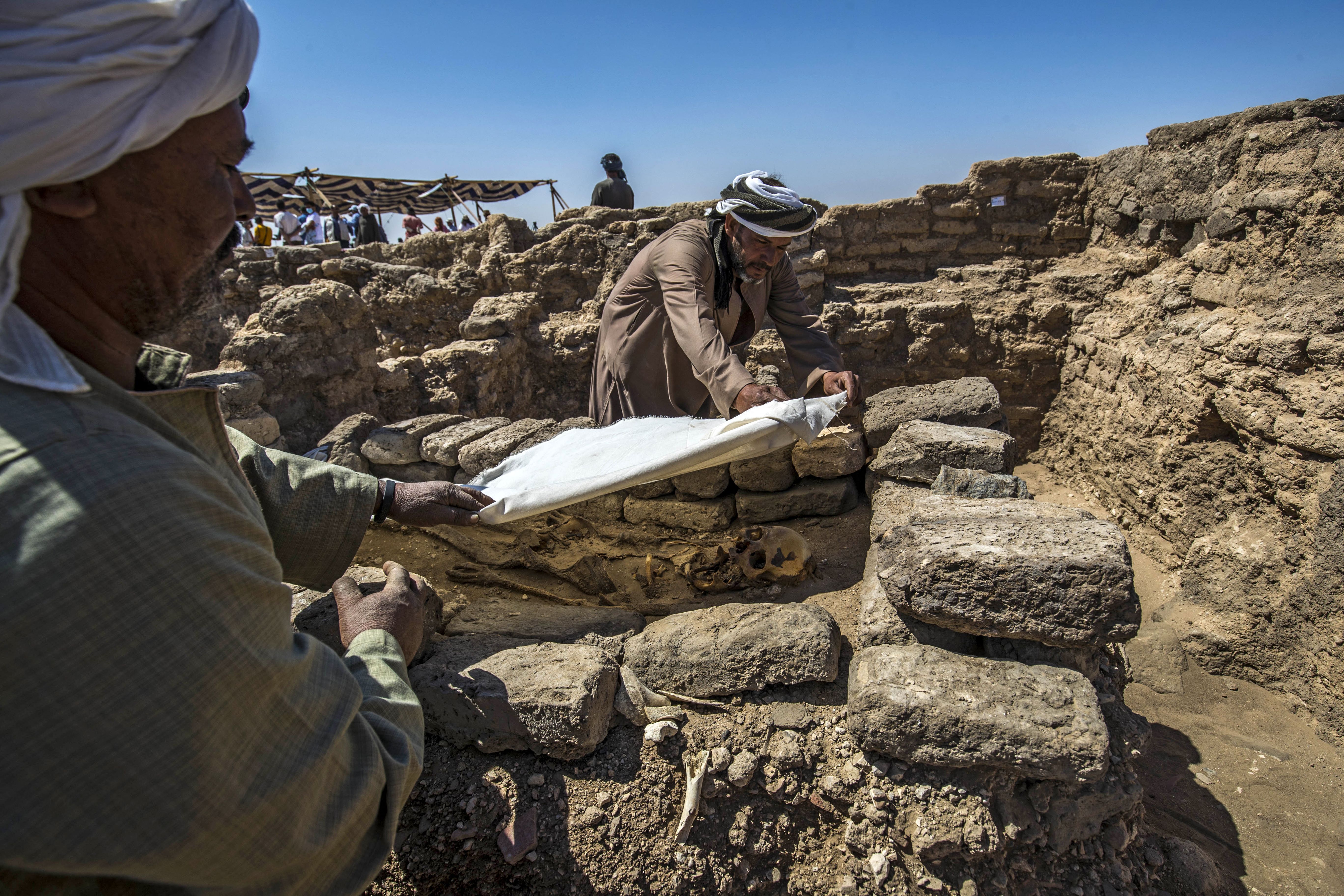 Workers covering a skeleton at the archaeological site of a 3000 year old city, dubbed The Rise of Aten, dating to the reign of Amenhotep III, uncovered by the Egyptian mission near Luxor. 