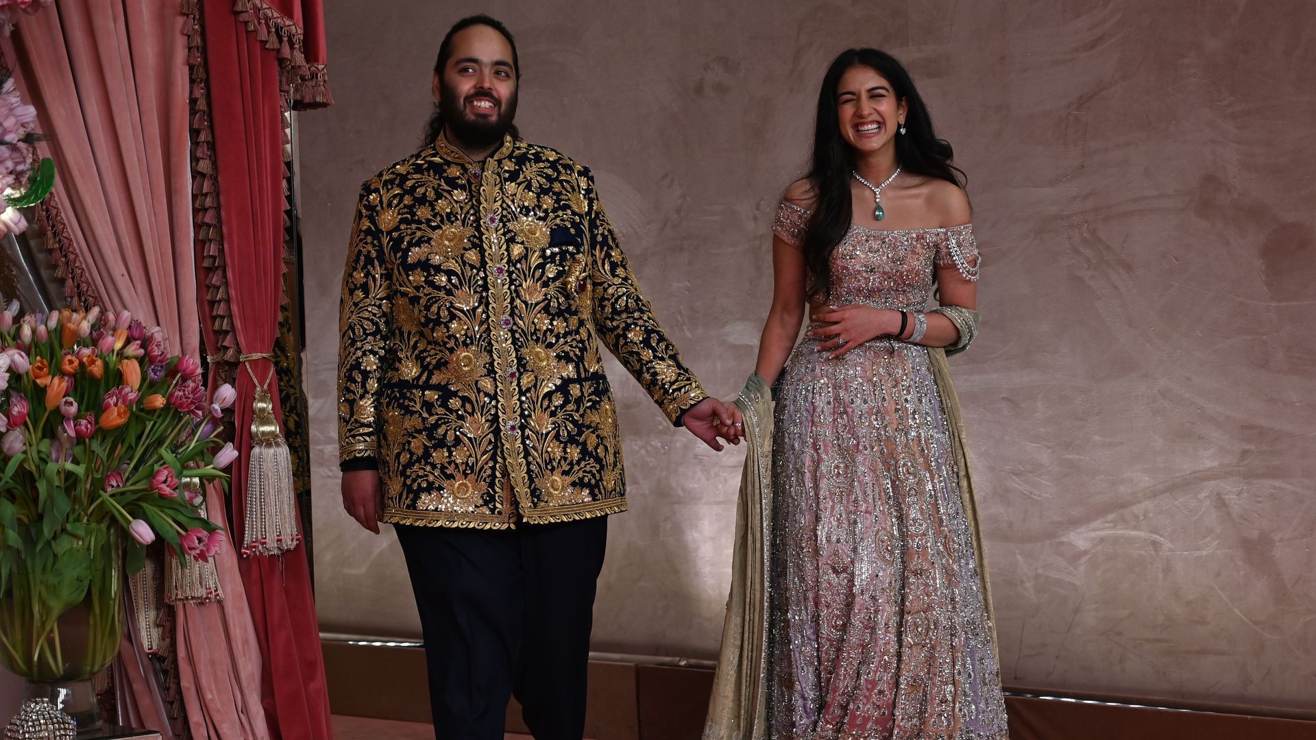 photo of a South Asian man and woman dressed in traditional ceremonial wedding attire holding hands