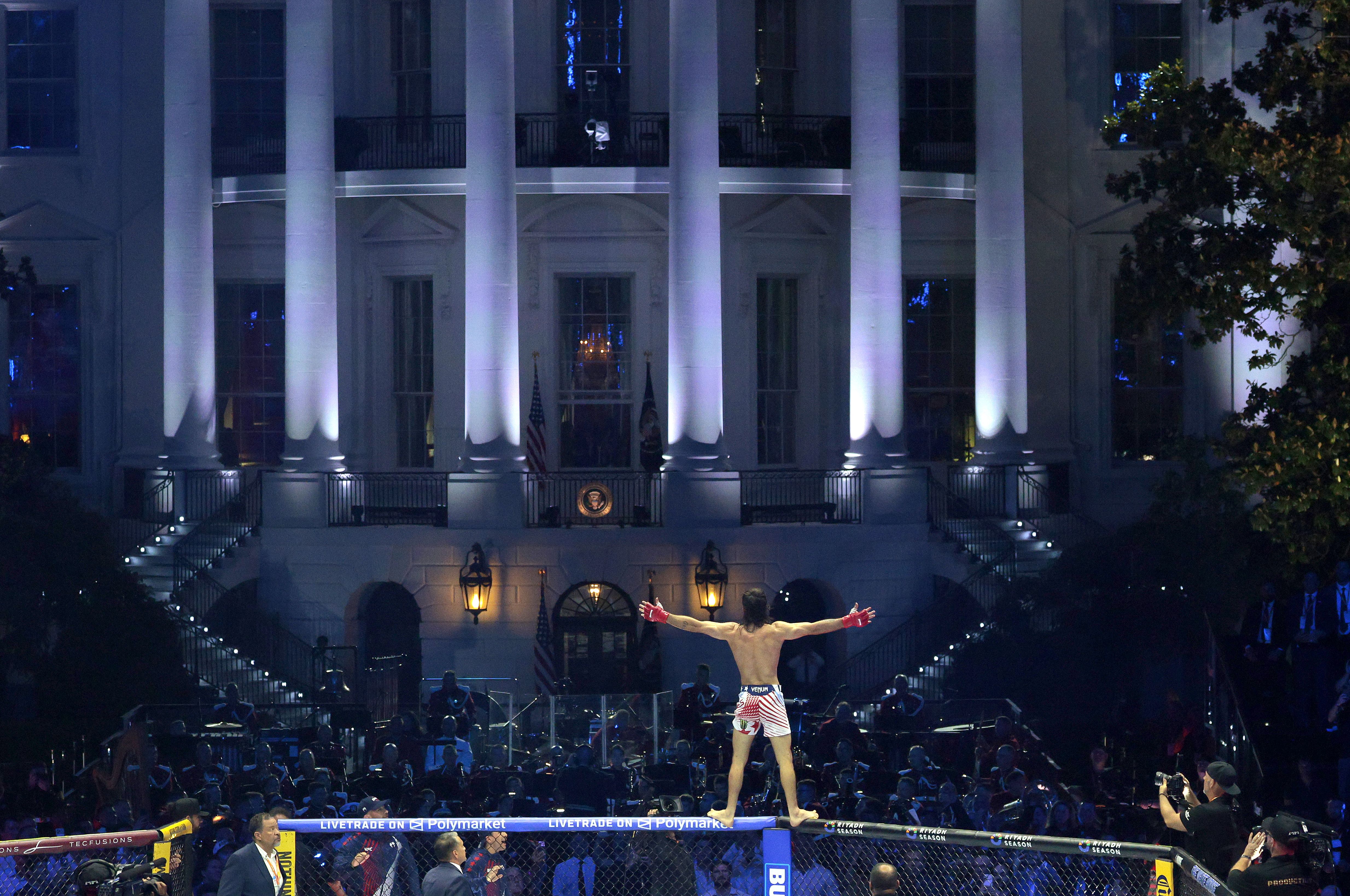 A UFC fighter stands with his arms outstretched. The White House is seen in the background.