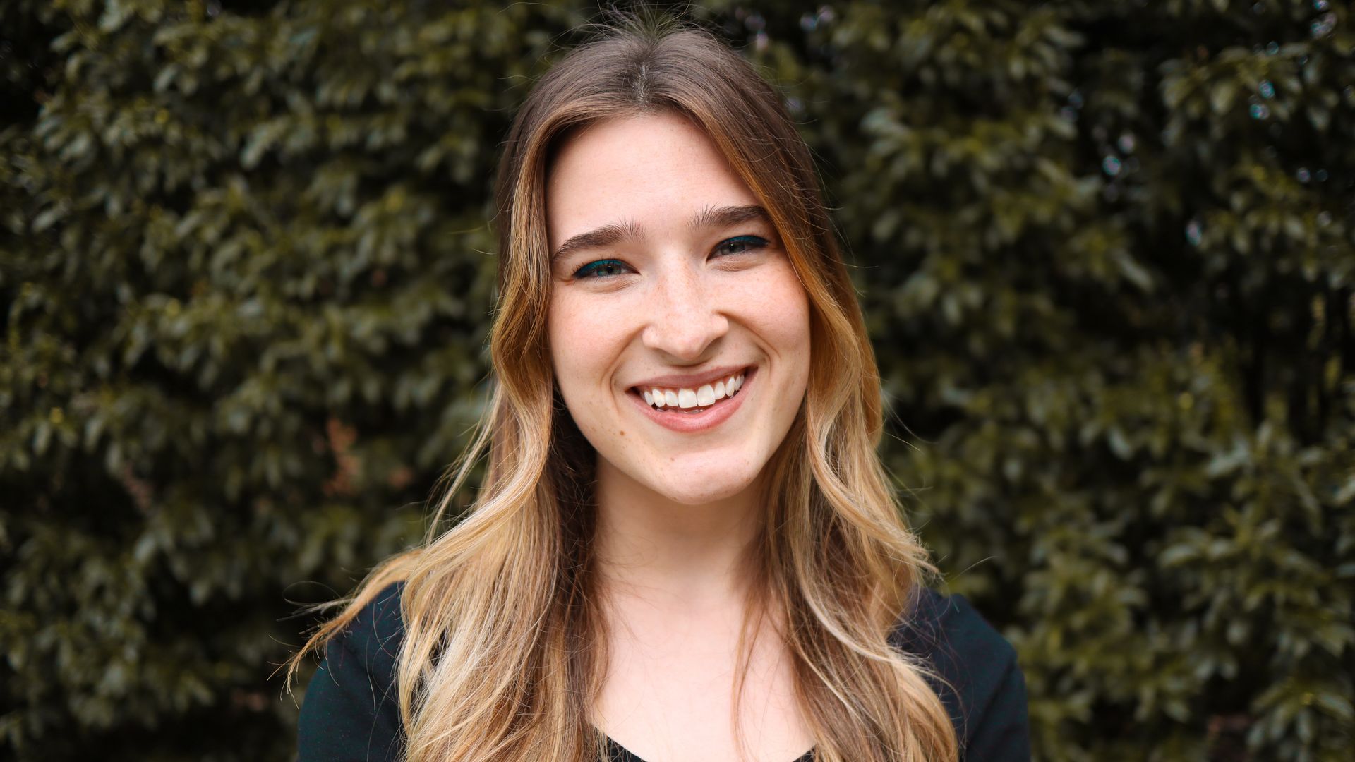 Photo of blonde woman in front of trees