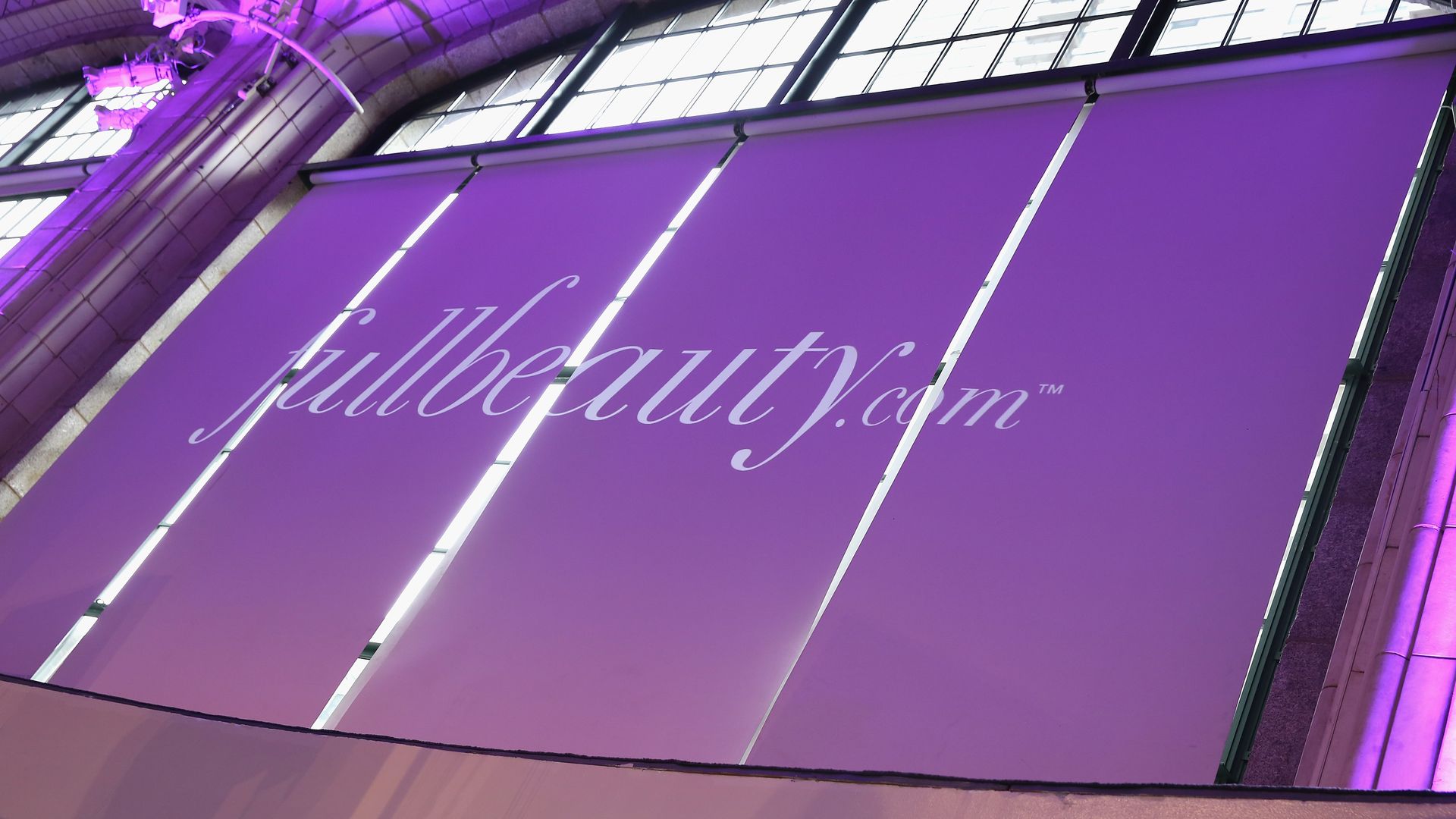 A canvas sign advertising apparel retailer Fullbeauty's website, with white lettering on a lilac background.