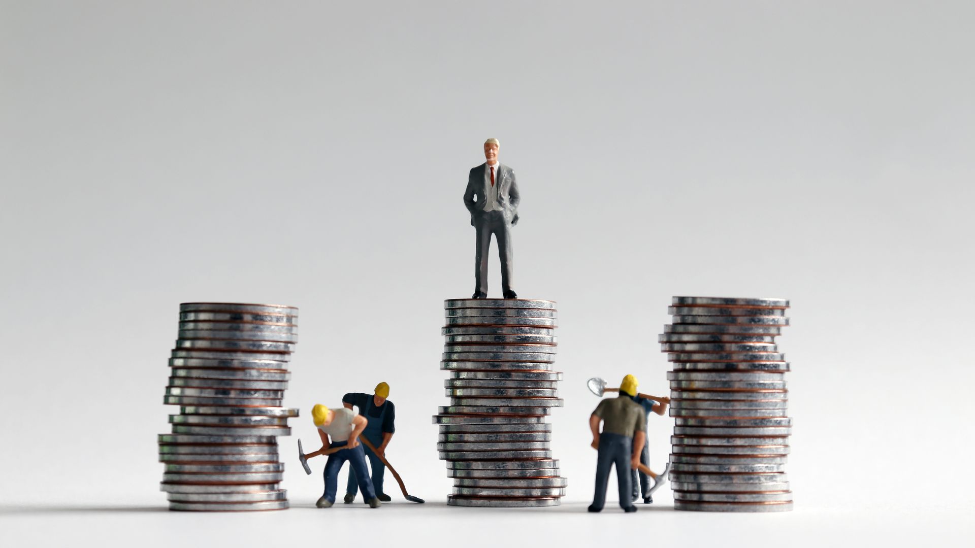 Miniature people and three pile of coins.