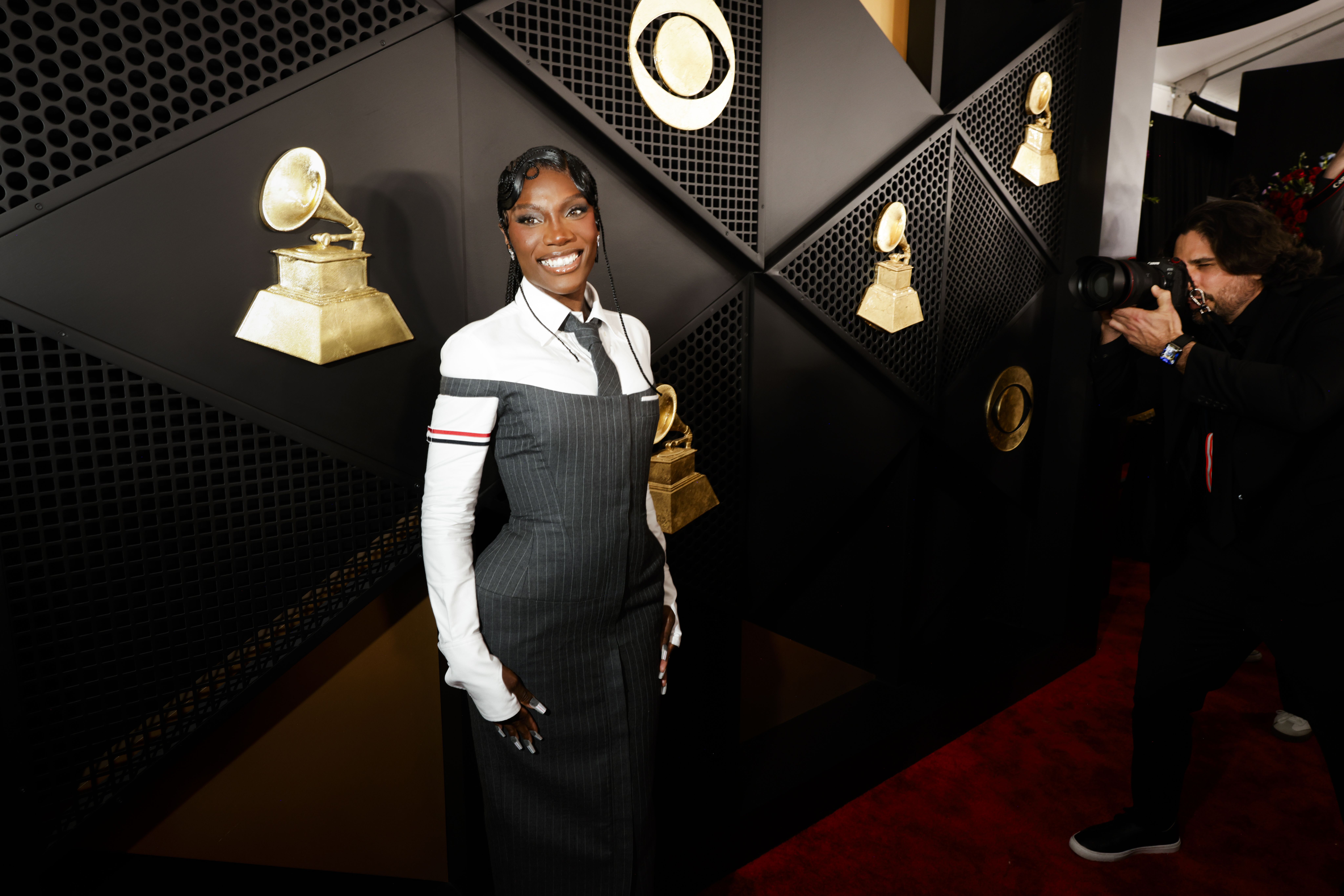 Photo of a woman standing in front of a wall with a recording device painted on it. 