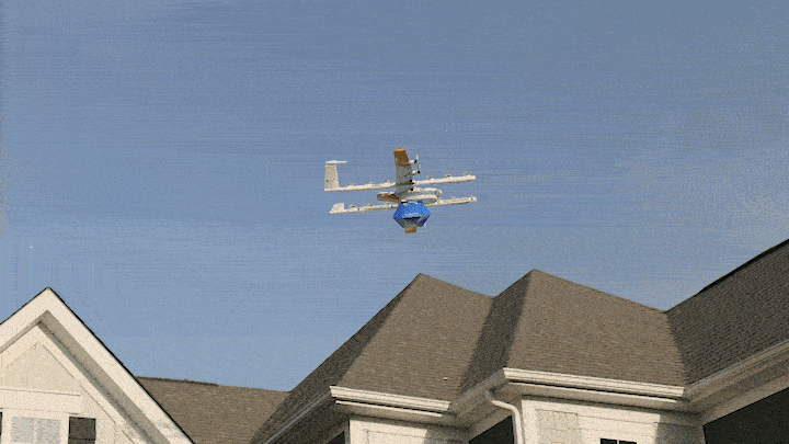 Image shows a drone dropping a package on a driveway.