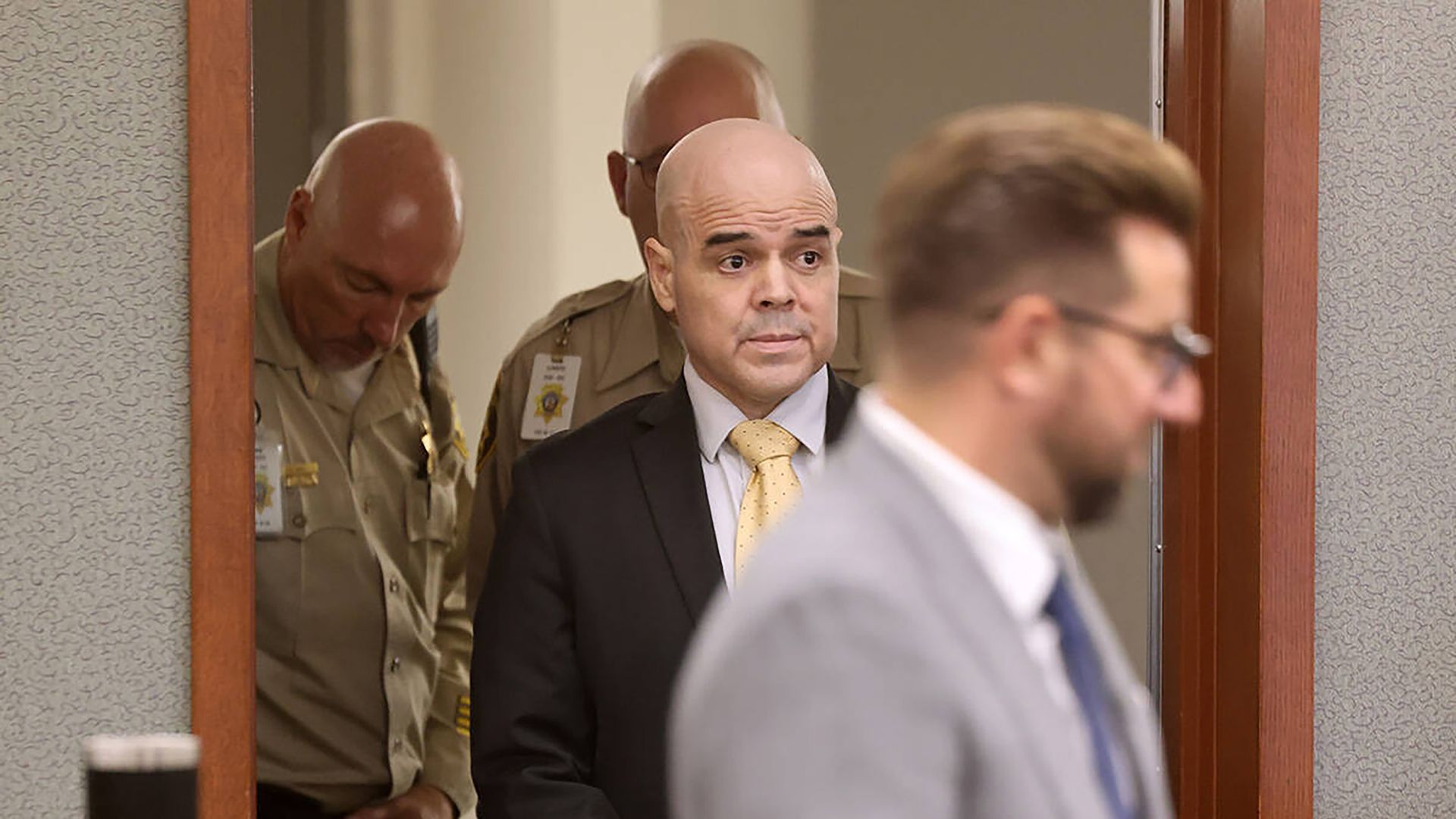 Robert Telles, wearing a suit, walks into court room. 