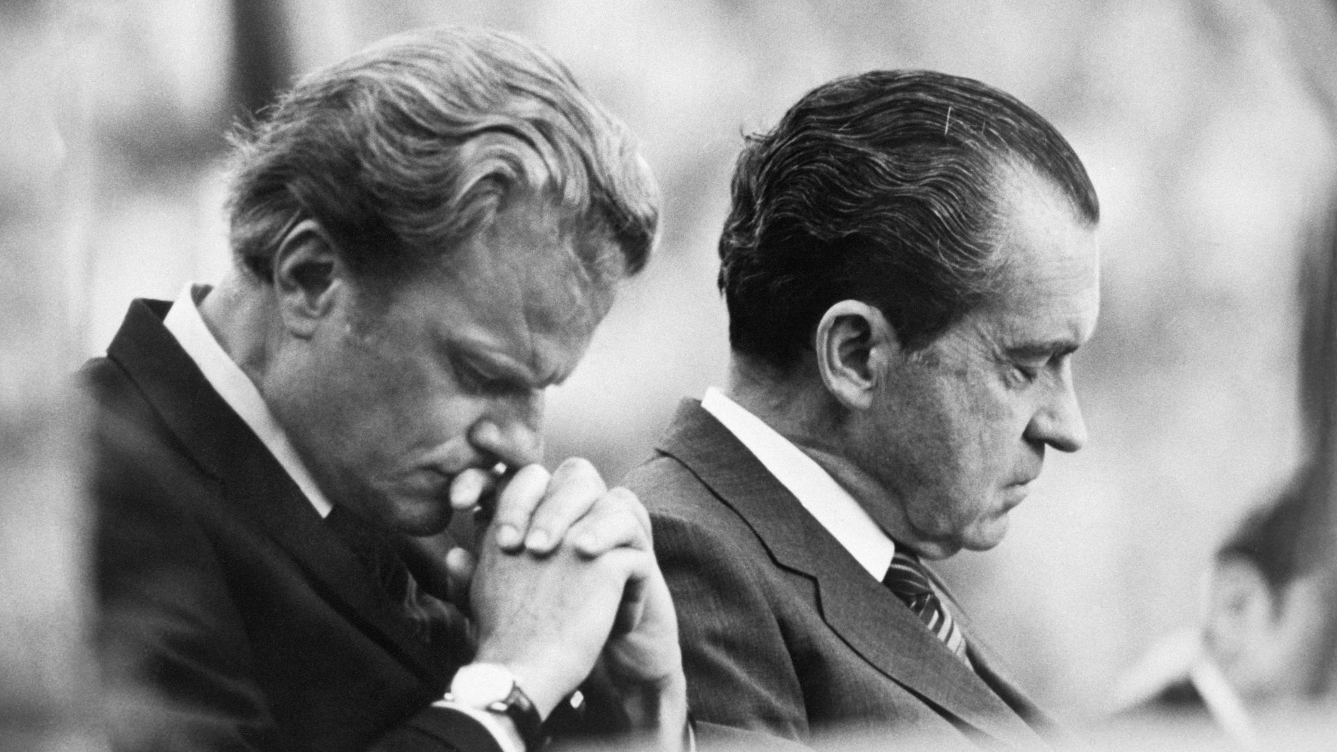 Graham and Nixon bow their heads in prayer